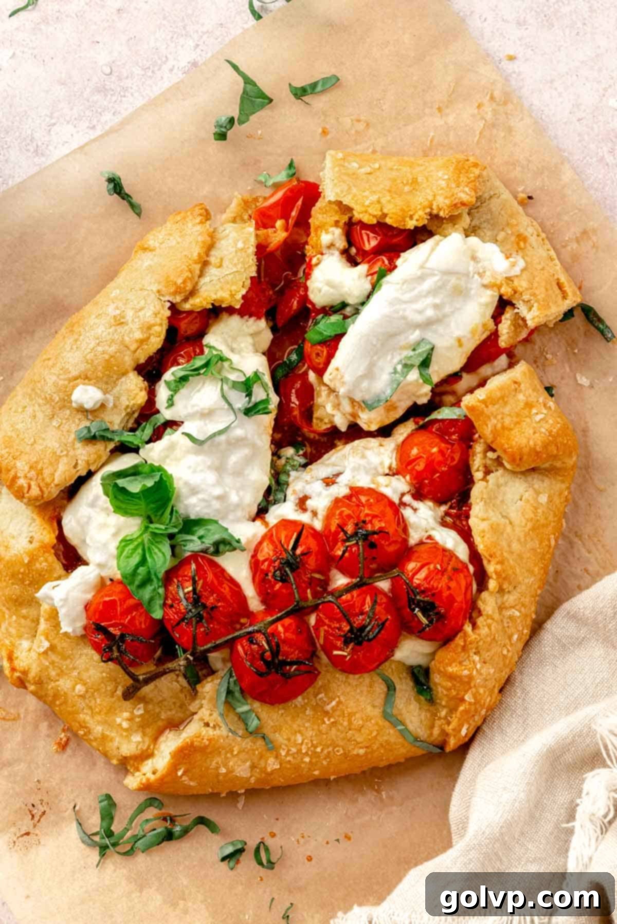 Slice of tomato galette topped with fresh mozzarella and basil on a white plate