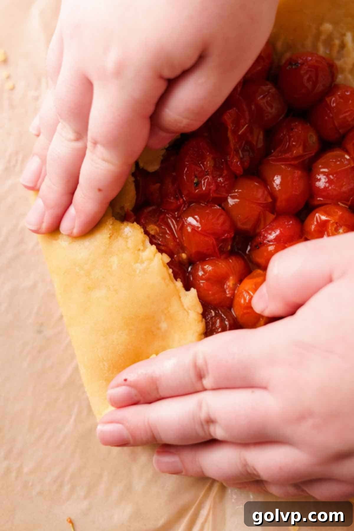 Using hands to neatly fold over the pastry edges to create the rustic round galette shape