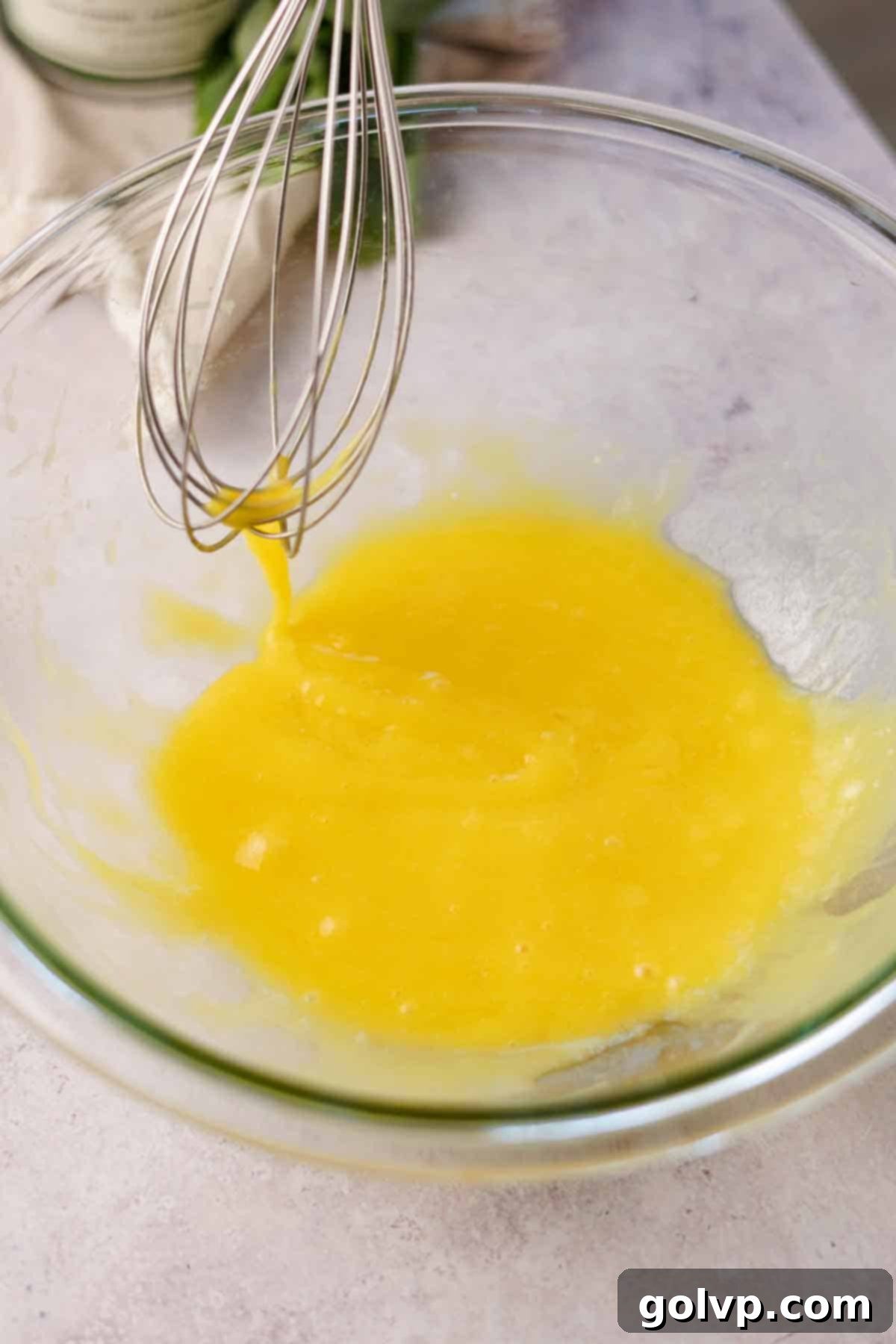 Whisking eggs and olive oil in a large glass bowl until smooth and emulsified
