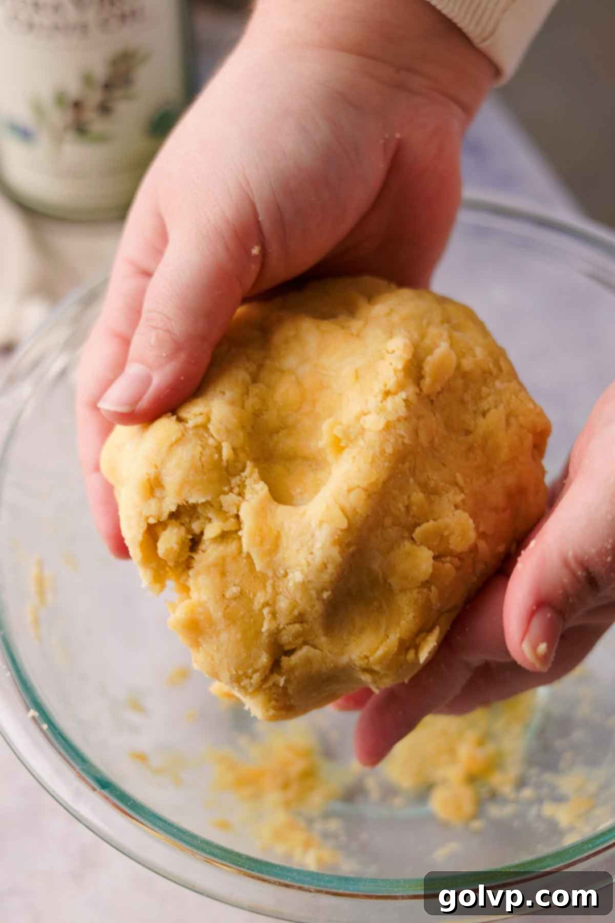 Holding a perfectly formed ball of olive oil pastry dough above a glass bowl