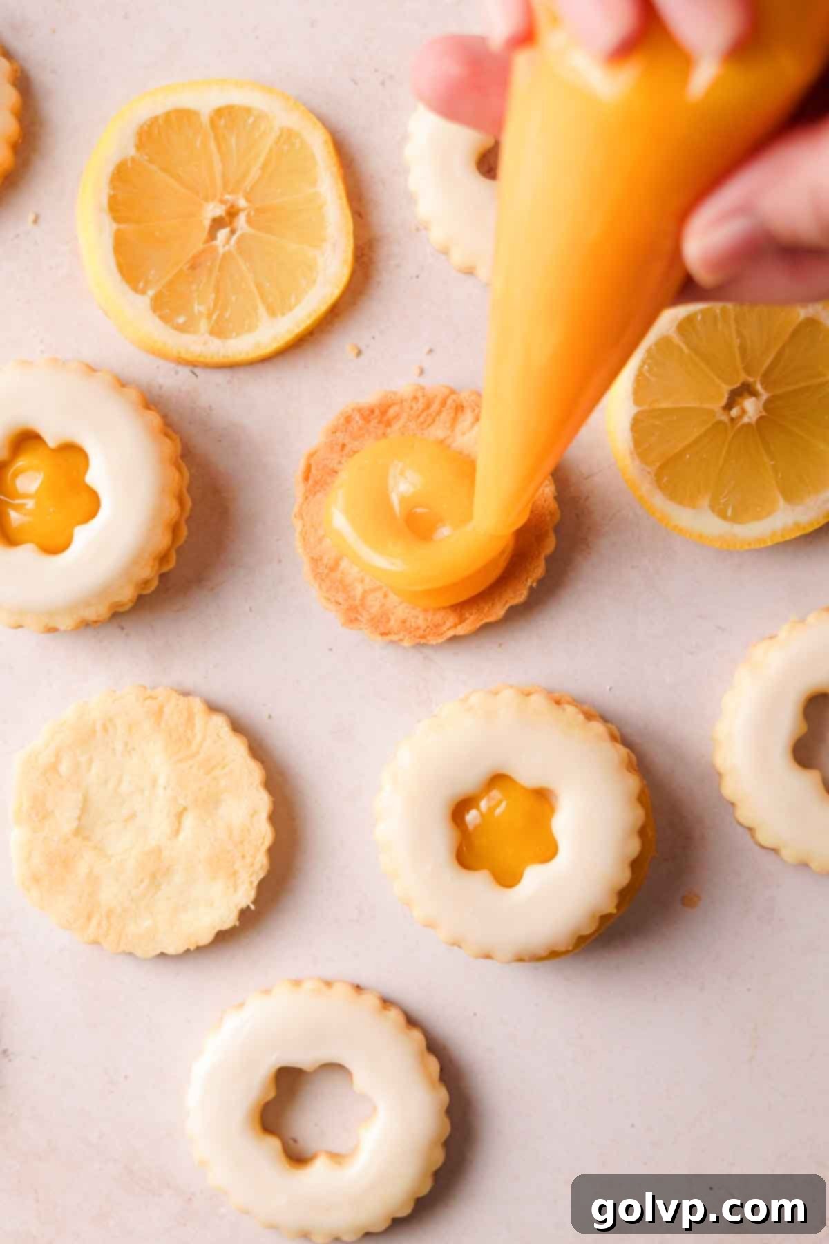 Using a piping bag to neatly fill the bottom halves of shortbread cookies with creamy lemon curd.