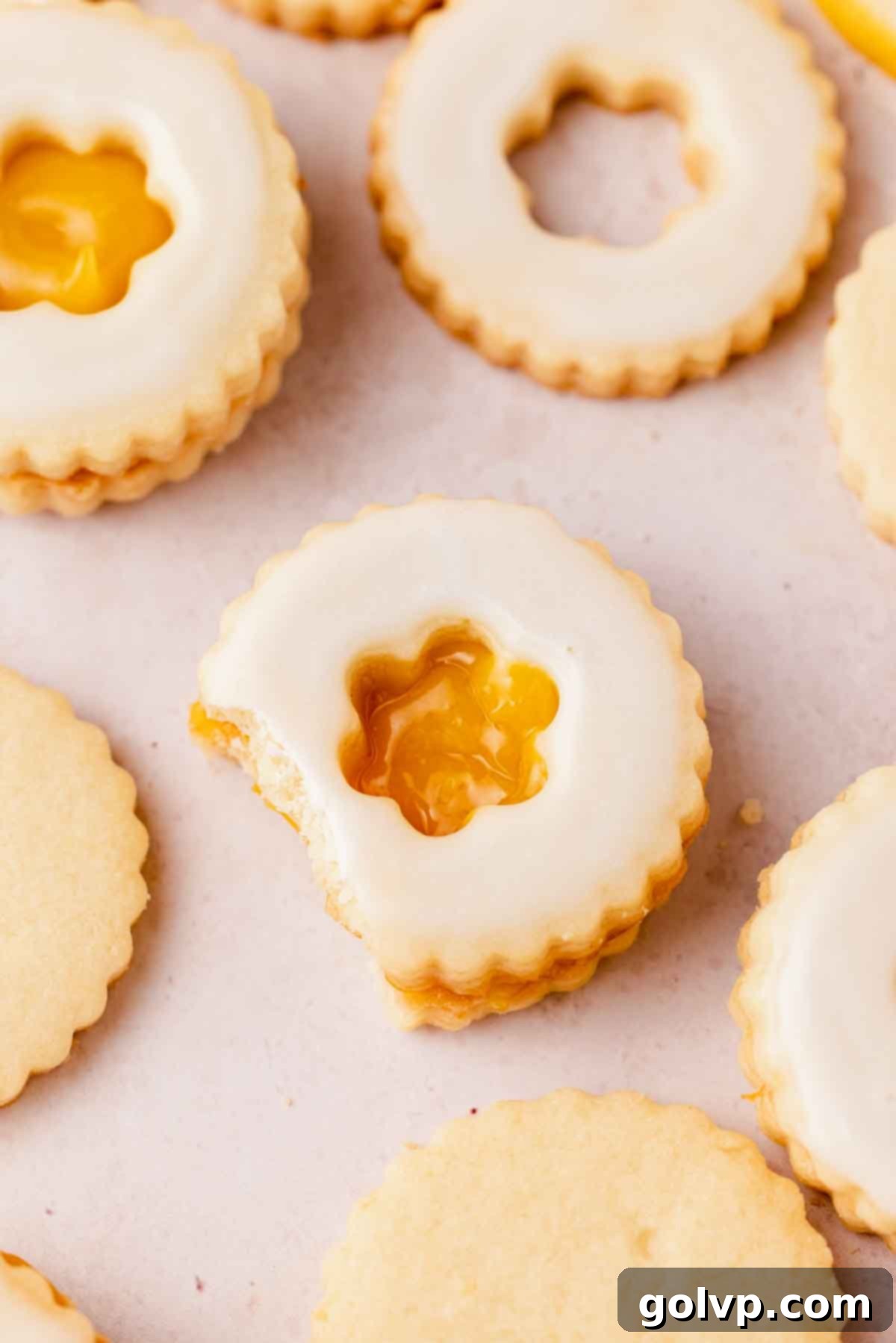 A bitten lemon curd filled shortbread cookie, showcasing the crisp shortbread, the gooey lemon curd, and the delicate lemon glaze.