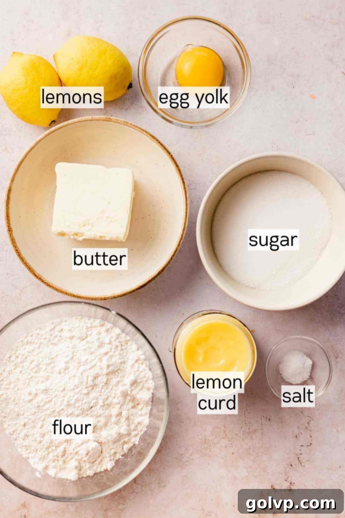 Various key ingredients for lemon shortbread cookies arranged in bowls, including lemons, butter, flour, and sugar.