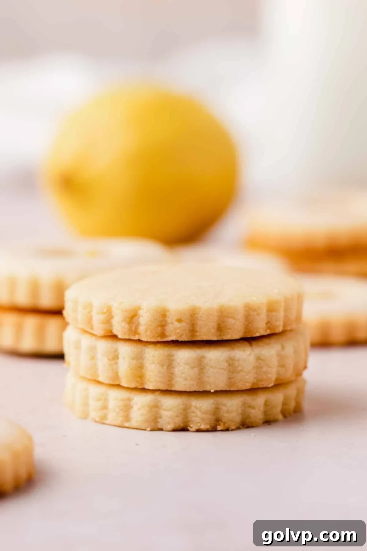 A neat stack of plain round lemon shortbread cookies with scalloped edges, ready for glazing or filling.