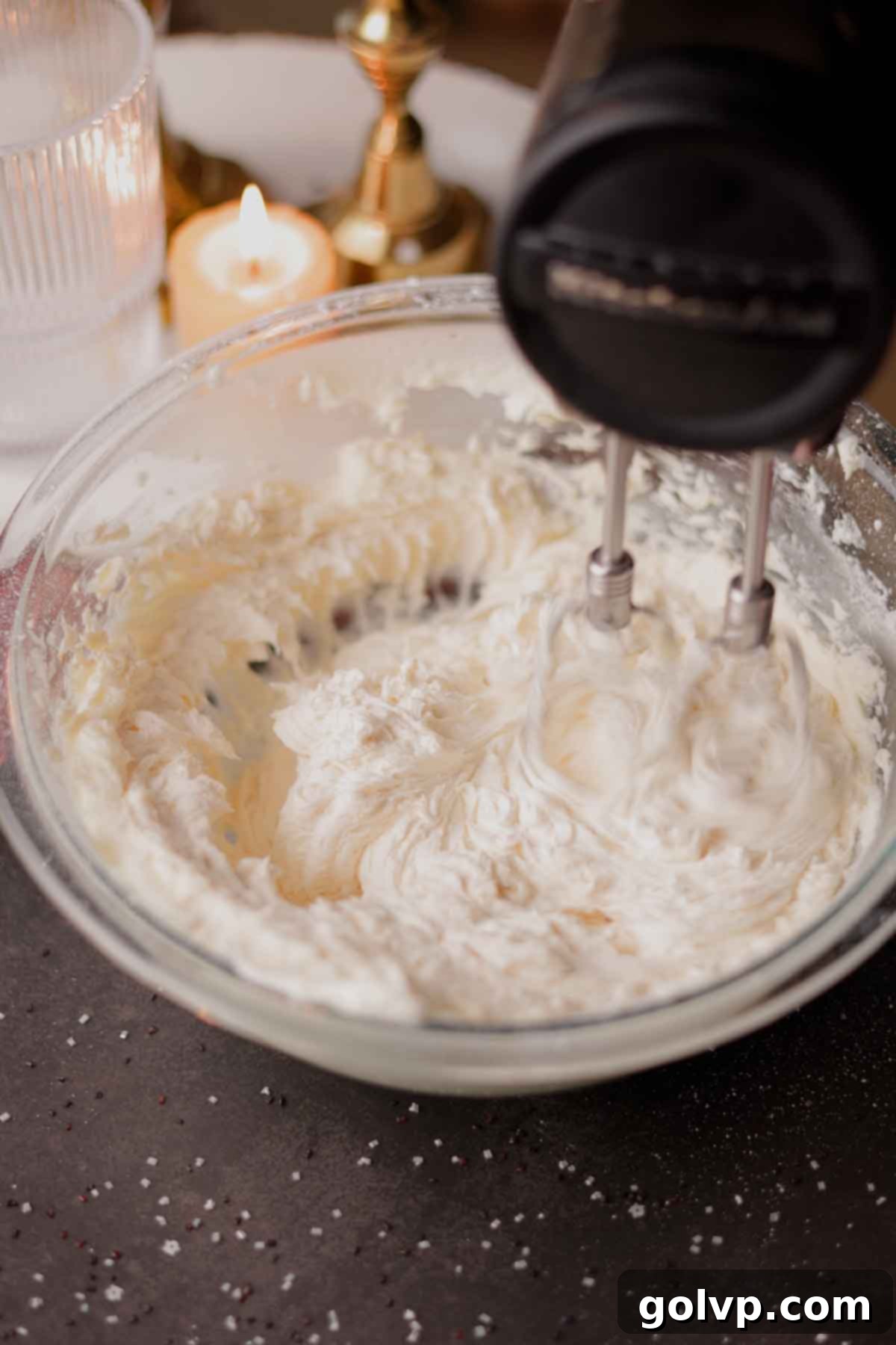 Butter and powdered sugar being beaten together with an electric mixer for the black velvet frosting.