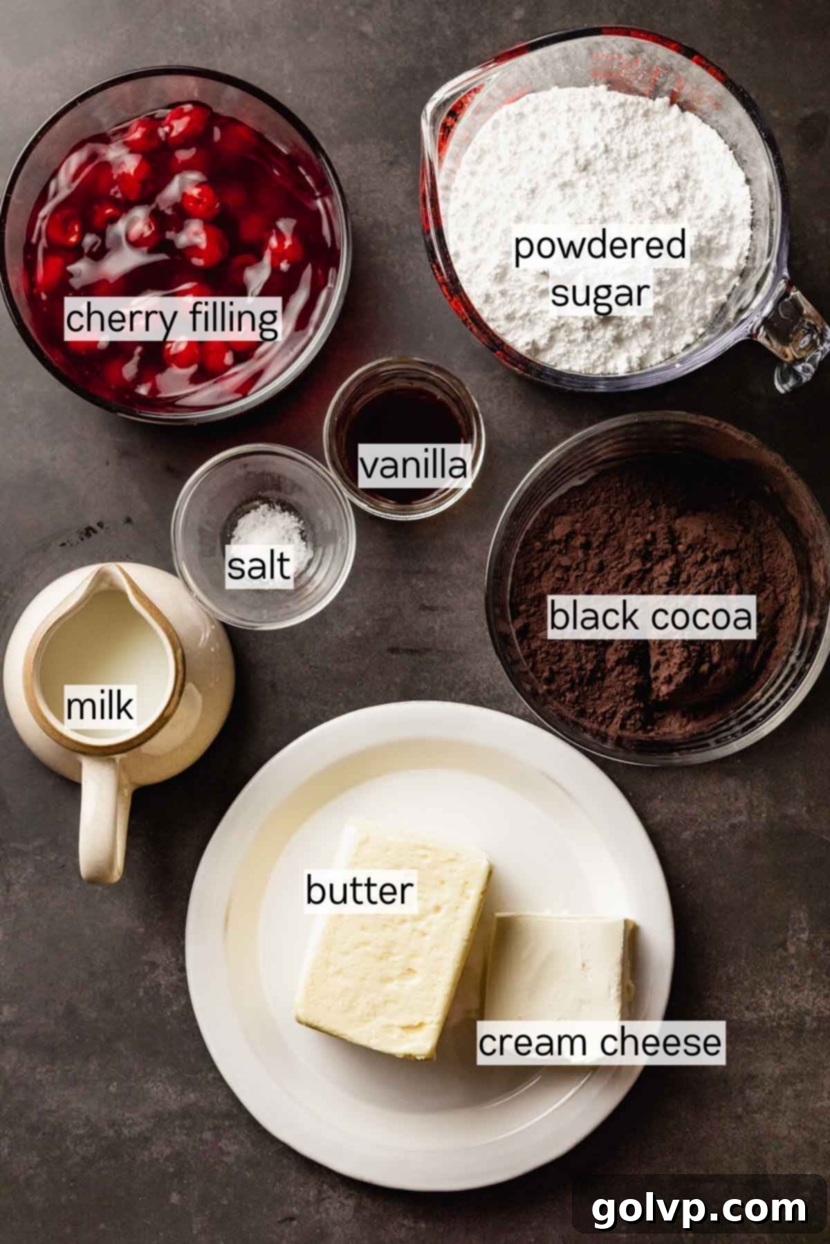 Ingredients for the black velvet frosting, including softened butter, cream cheese, and black cocoa powder, arranged in bowls.