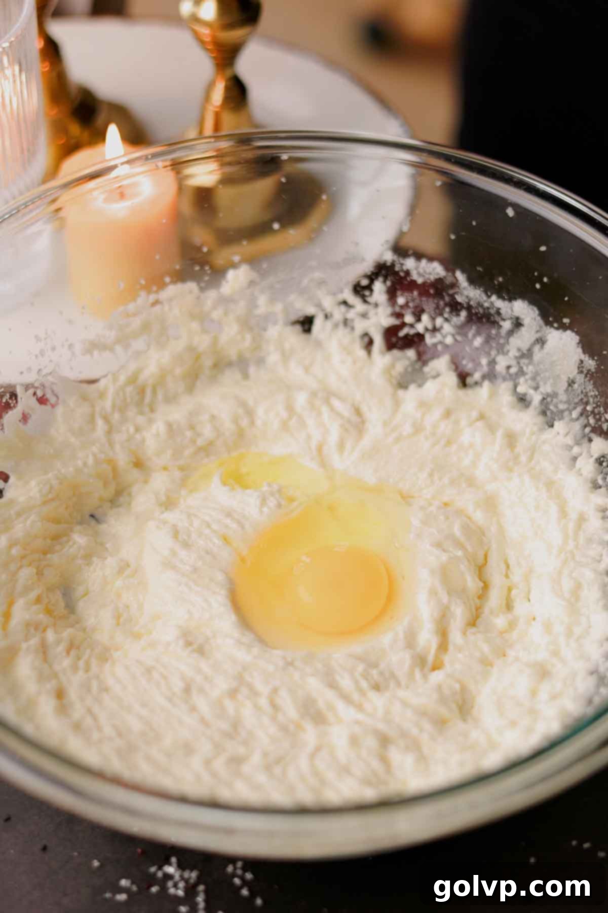 An egg being cracked into the light and fluffy butter, oil, and sugar mixture.