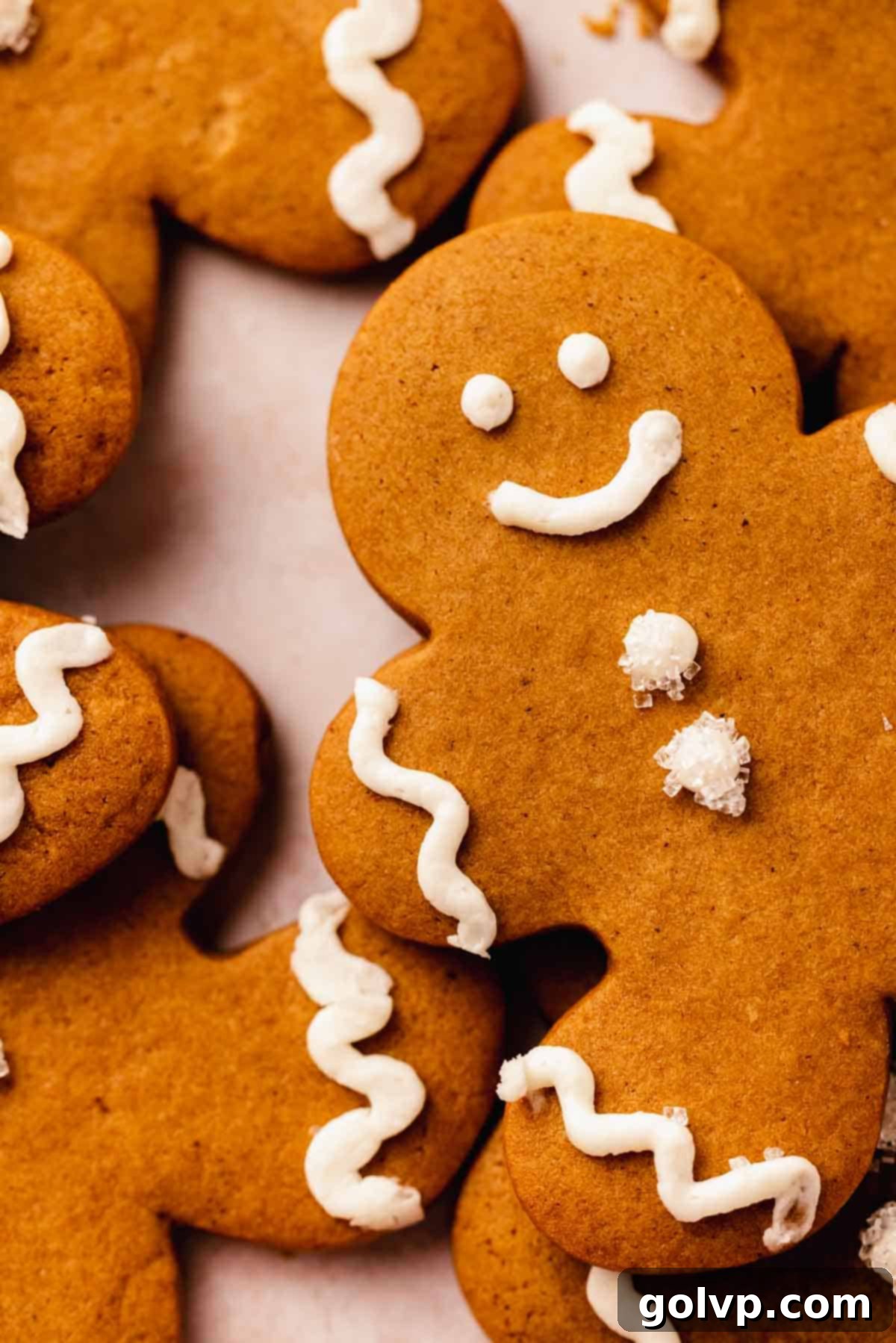 Close-up of a decorated gingerbread man cookie, showing intricate piped buttercream details and sparkly sugar on the buttons