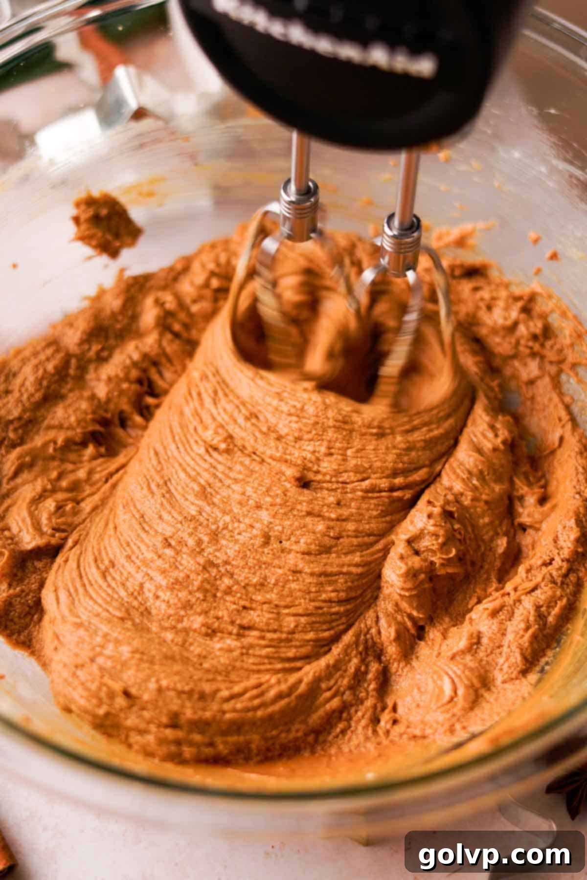 Mixing butter, sugar, egg, vanilla, and molasses to form a smooth gingerbread cookie dough base
