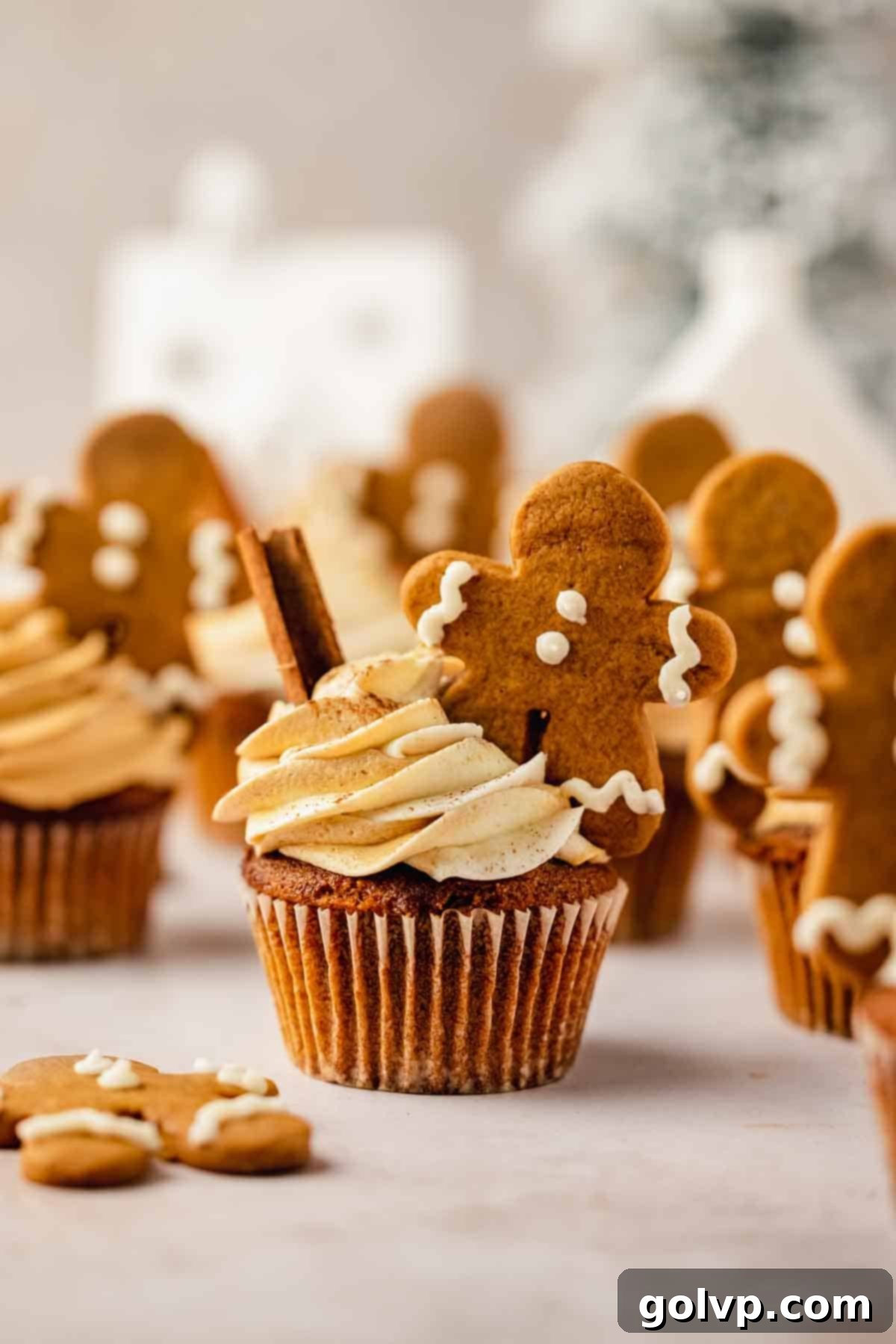 gingerbread cupcakes with gingerbread frosting and mini gingerbread men with evergreen tree in the back