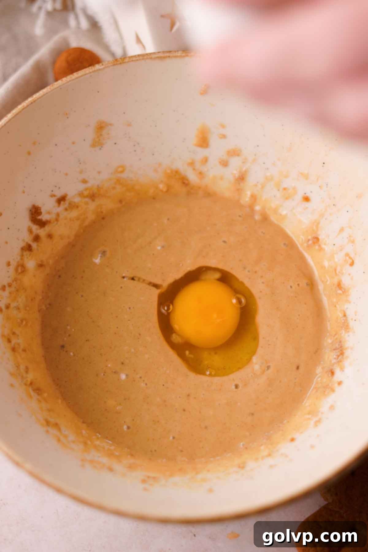 cracking an egg into the bowl of wet ingredients