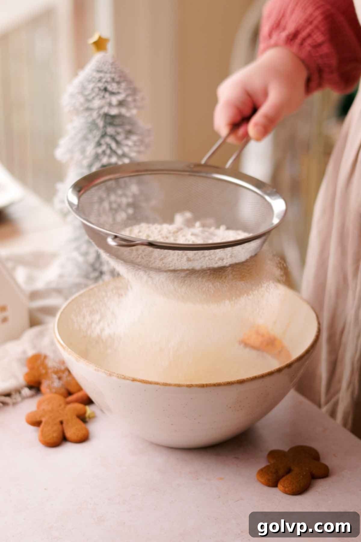 sift flour into the bowl of gingerbread cupcake batter
