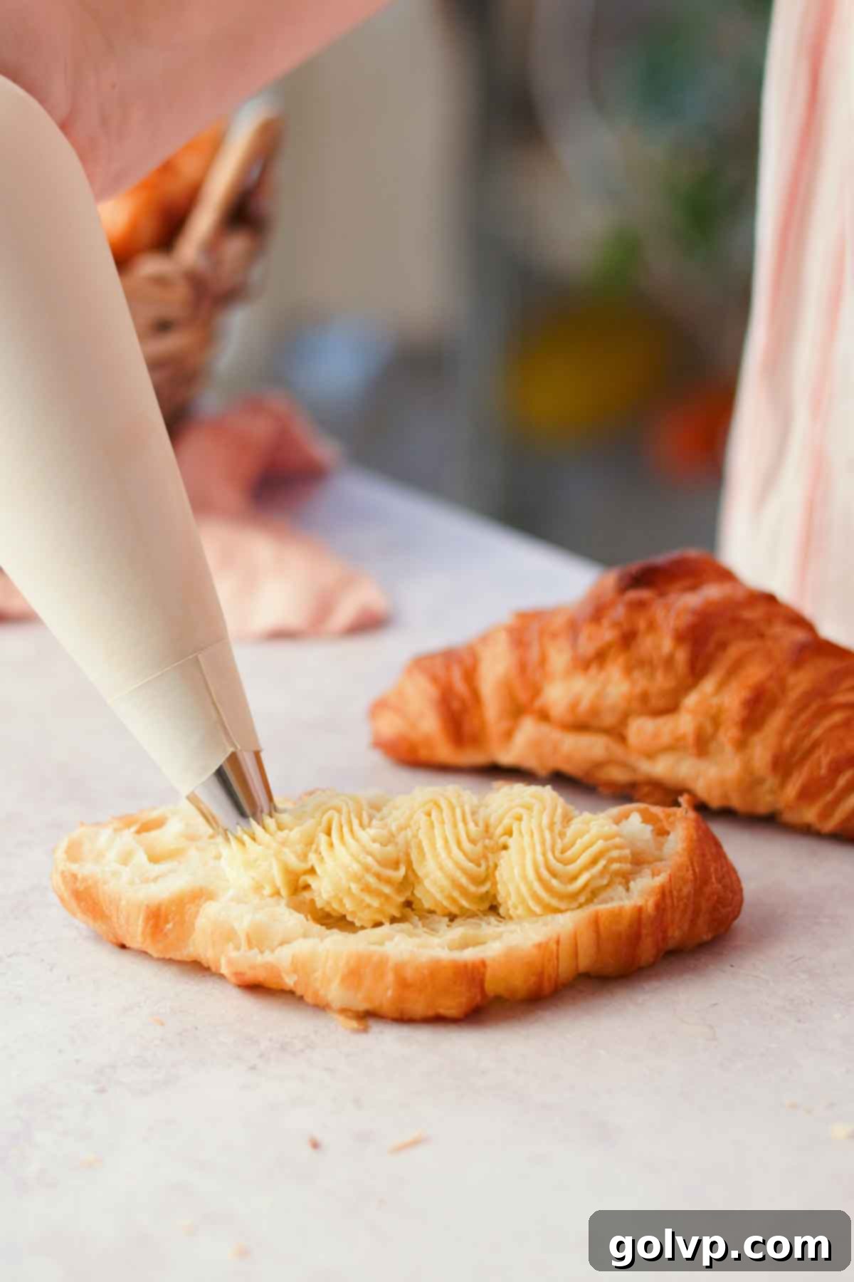 piping almond frangipane filling inside of croissant with piping bag