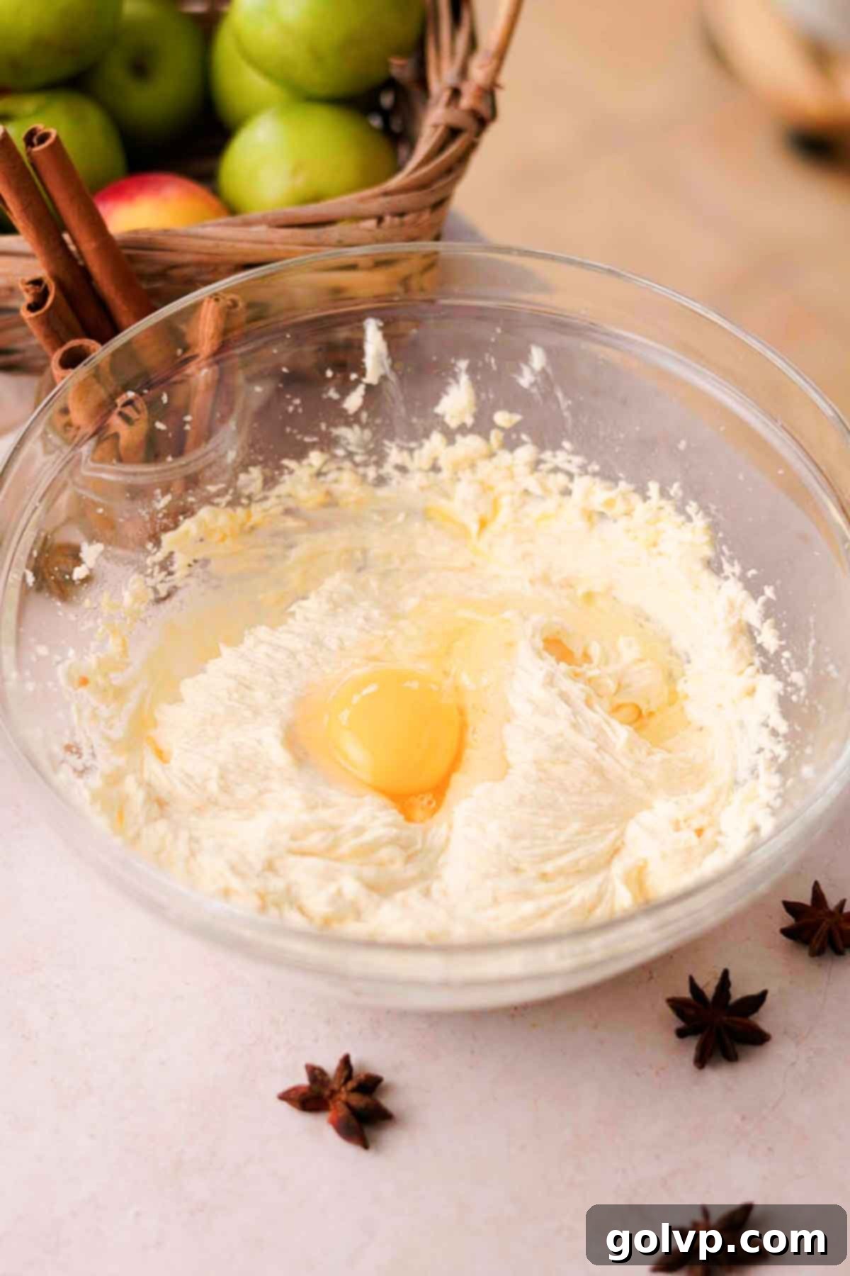 adding egg into chai cake batter in glass bowl