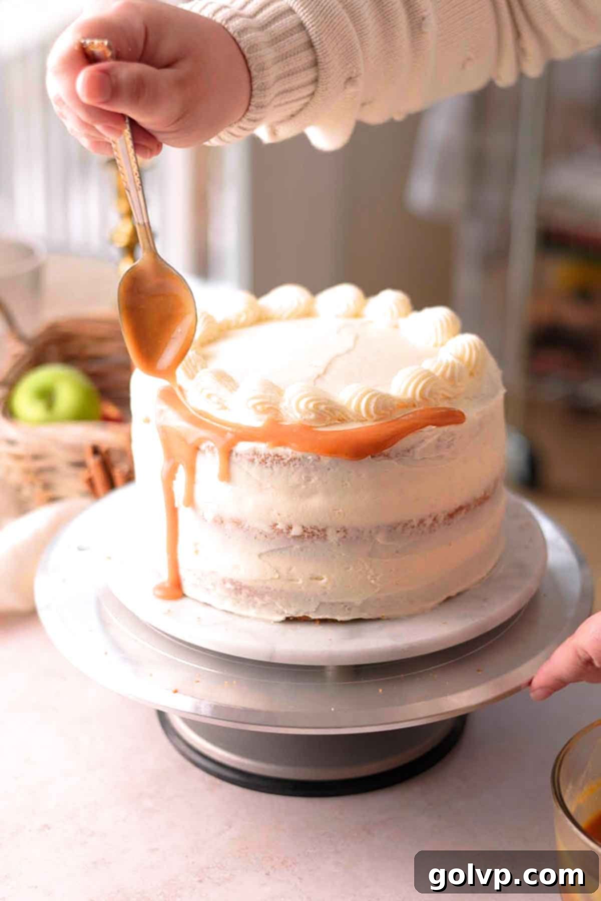 dripping caramel sauce off the edge of the cake with a spoon
