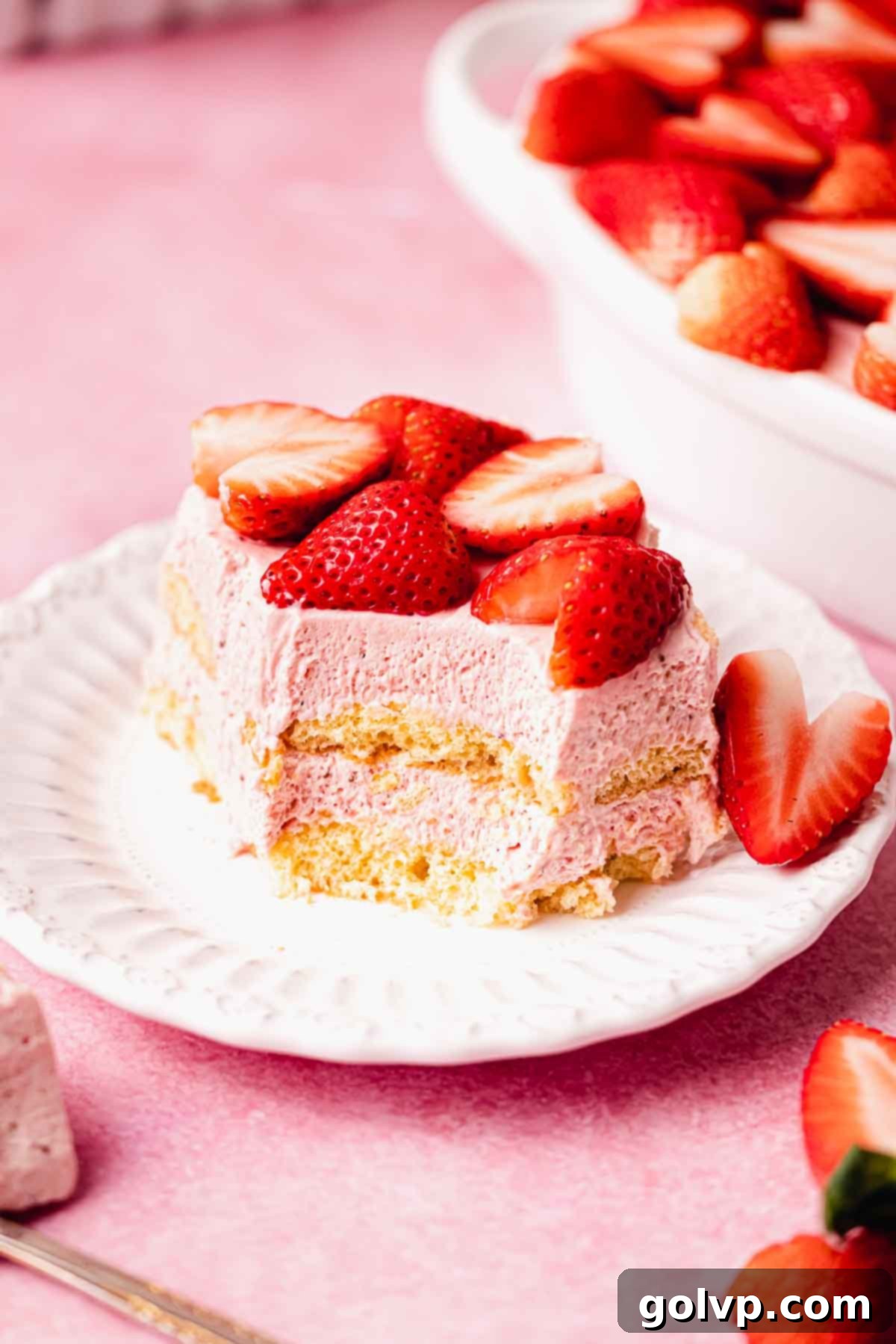 sliced strawberry tiramisu on plate with fresh strawberries on top
