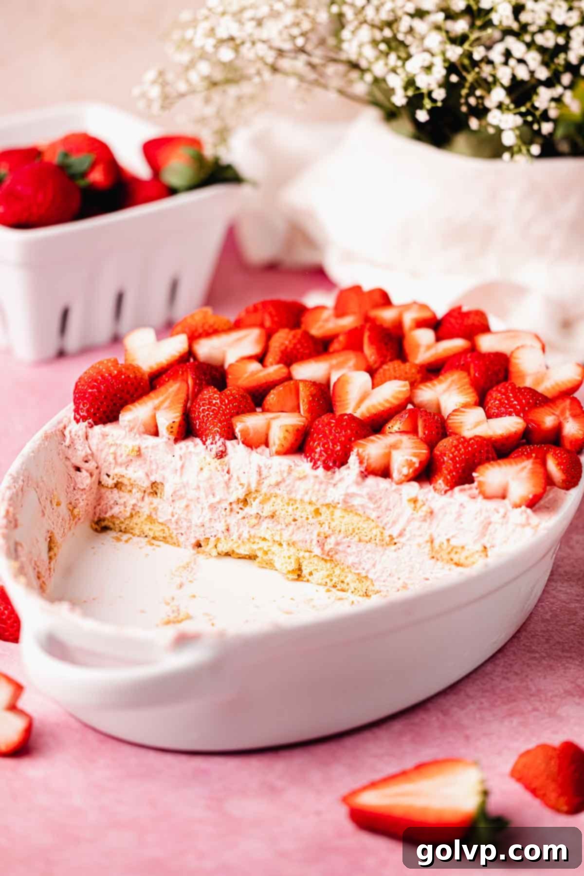 half a strawberry tiramisu in white dish with fresh strawberries on top