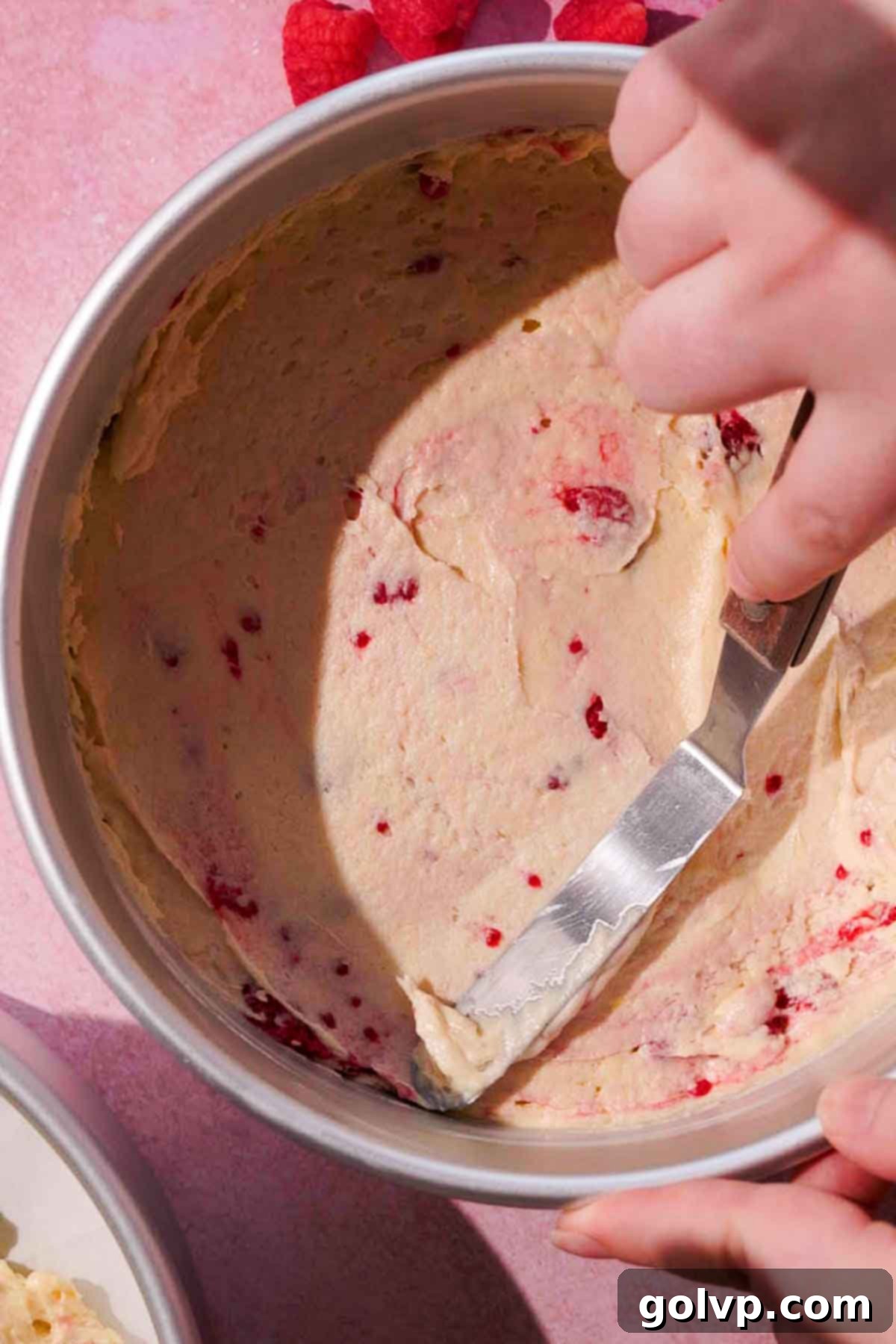 smoothing lemon raspberry cake batter into cake pan 