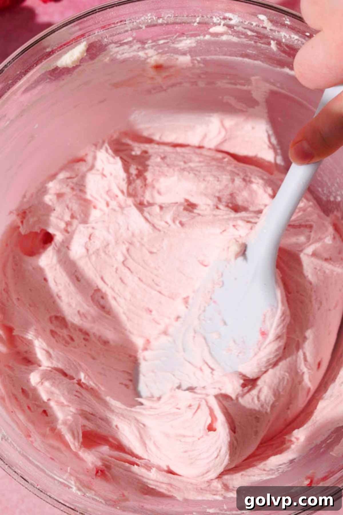 folding raspberry cream cheese frosting with silicone spatula