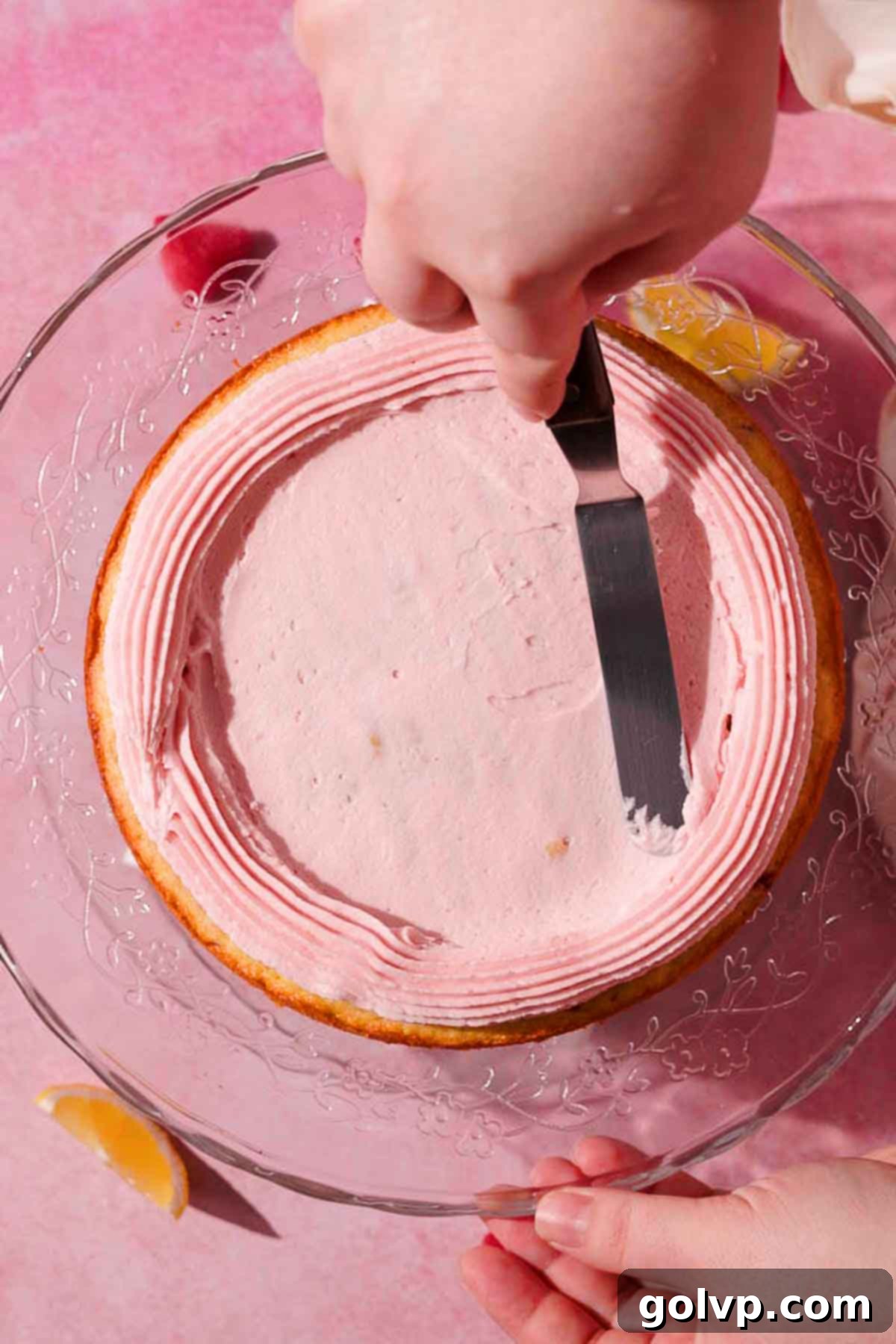 spreading thin layer of frosting on top of cake layer with a metal spatula 