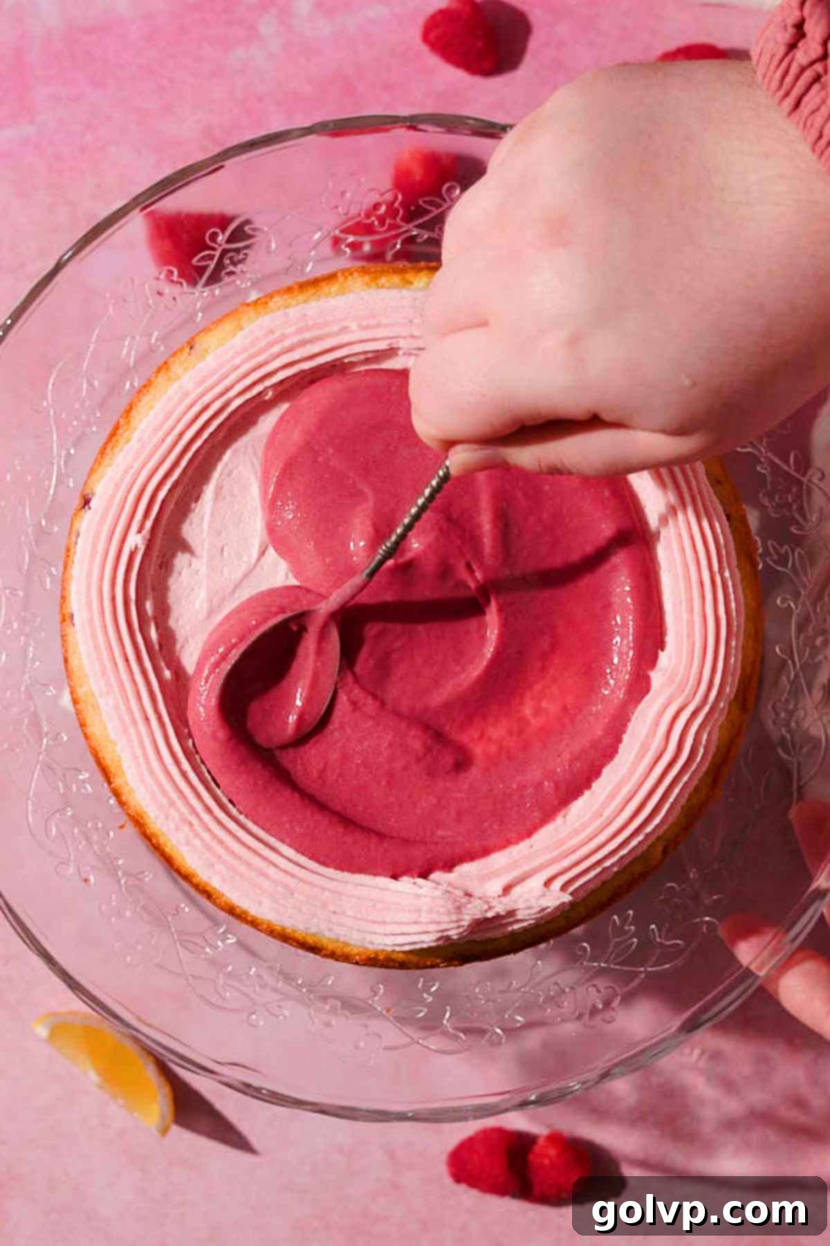 spreading raspberry curd into the middle of the cake with a piped border of frosting