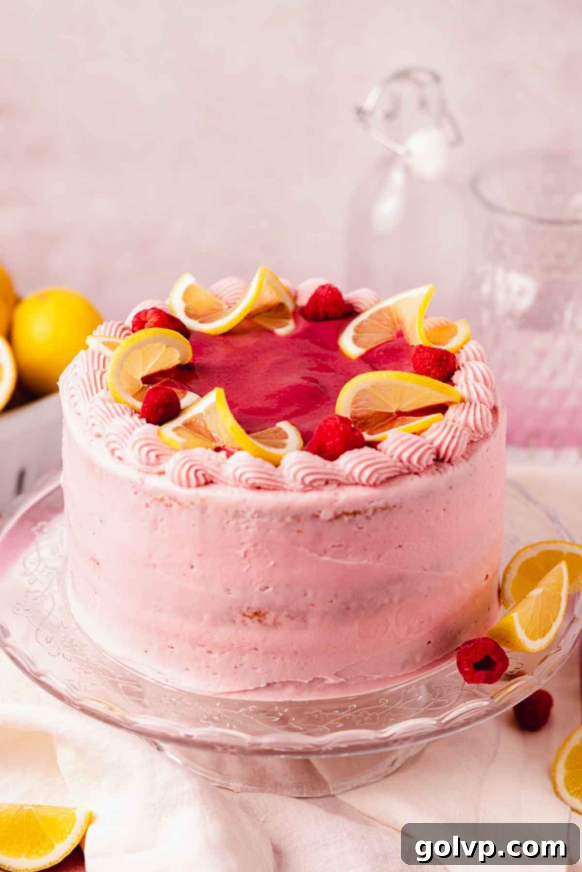 cake with pink raspberry frosting and fresh lemon slices on top