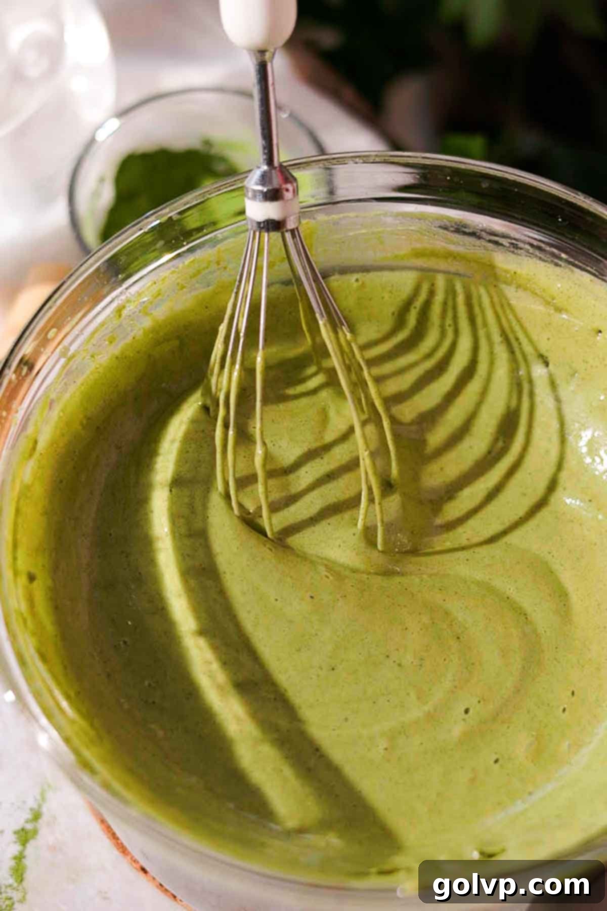 stirring the now thickened and foamy matcha custard filling with a wire whisk