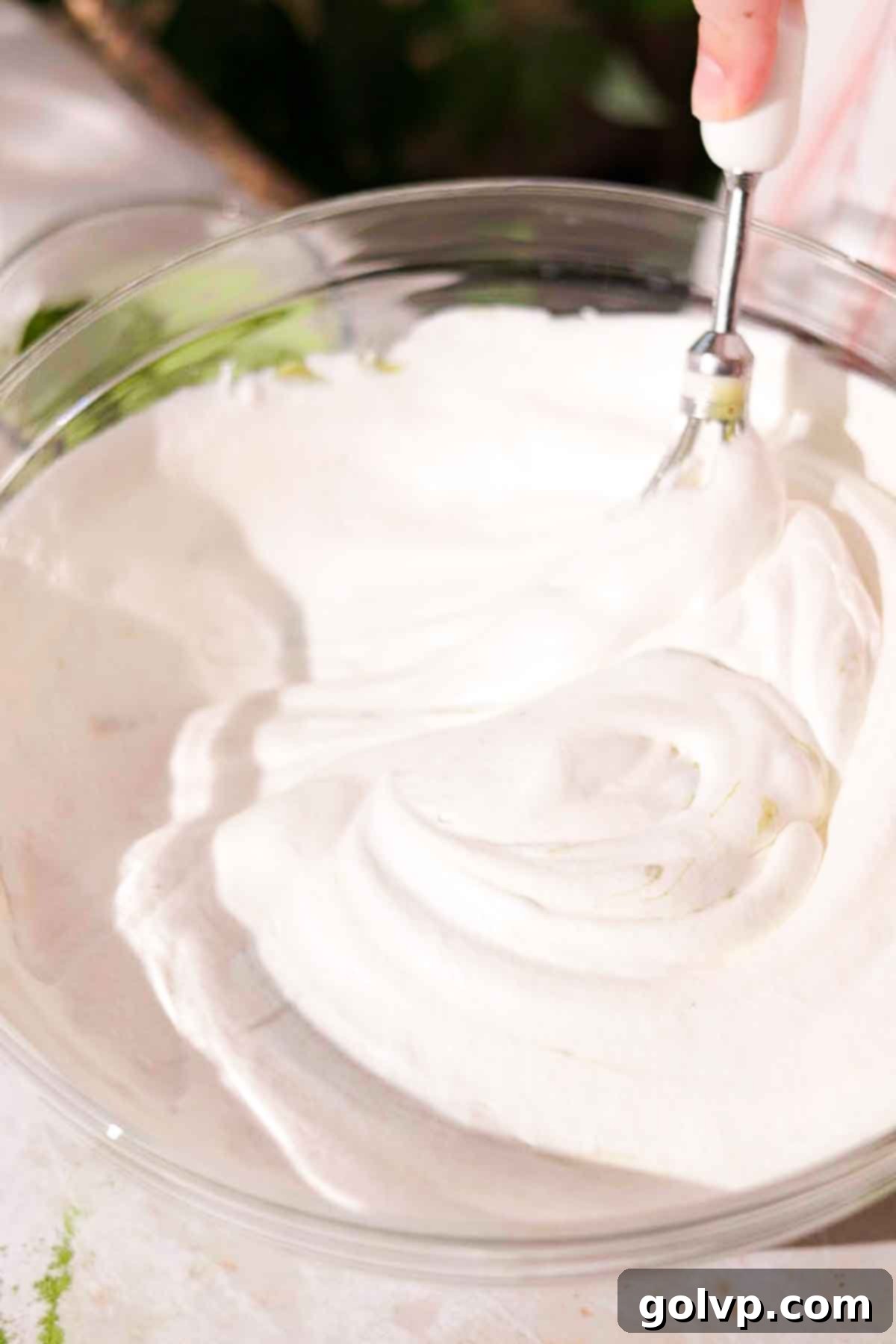 whipping heavy cream to stiff peaks in a large glass bowl using an electric mixer