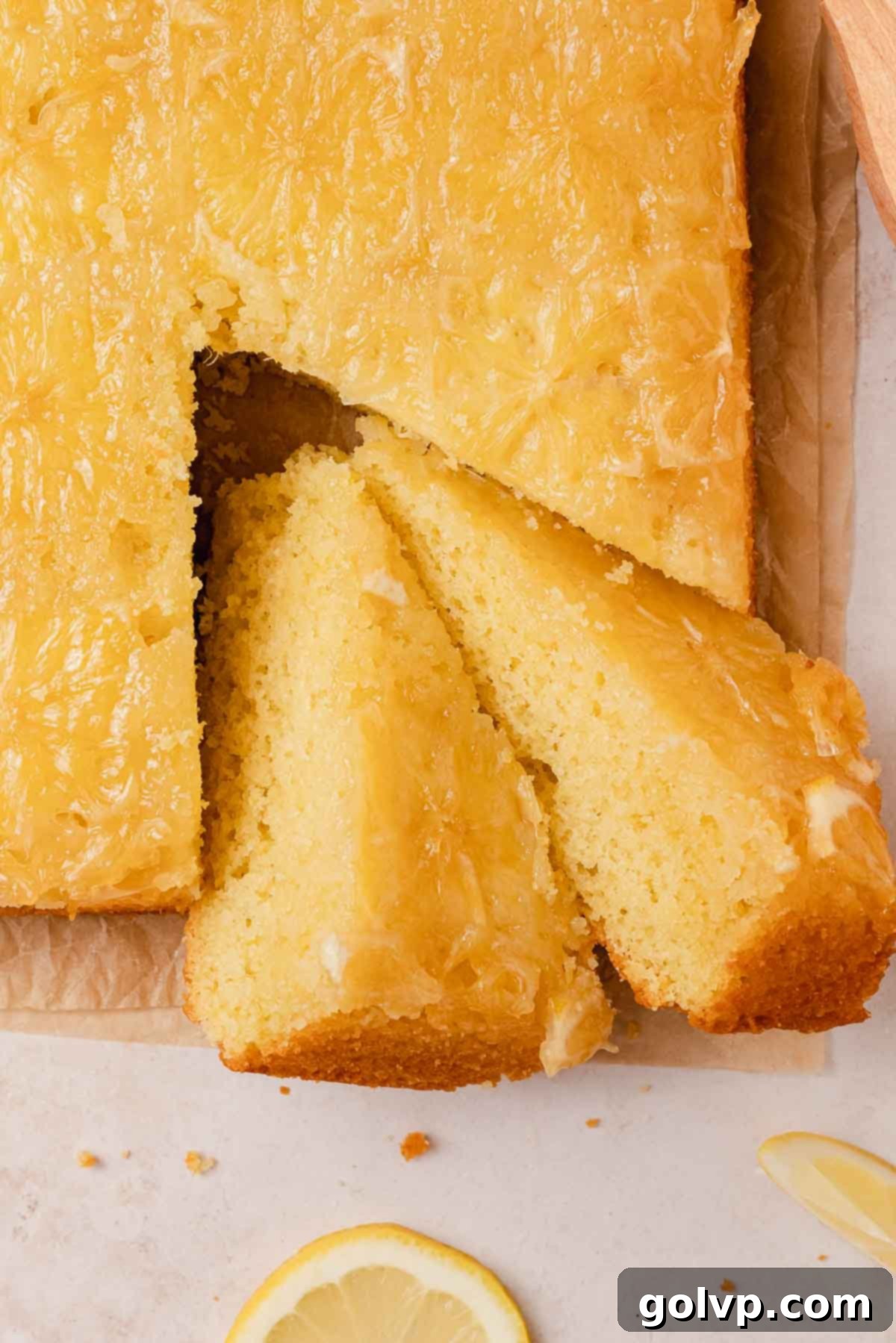 A close-up of a square slice of lemon olive oil cake, beautifully showing the candied lemon slices baked into the golden top and its moist texture.