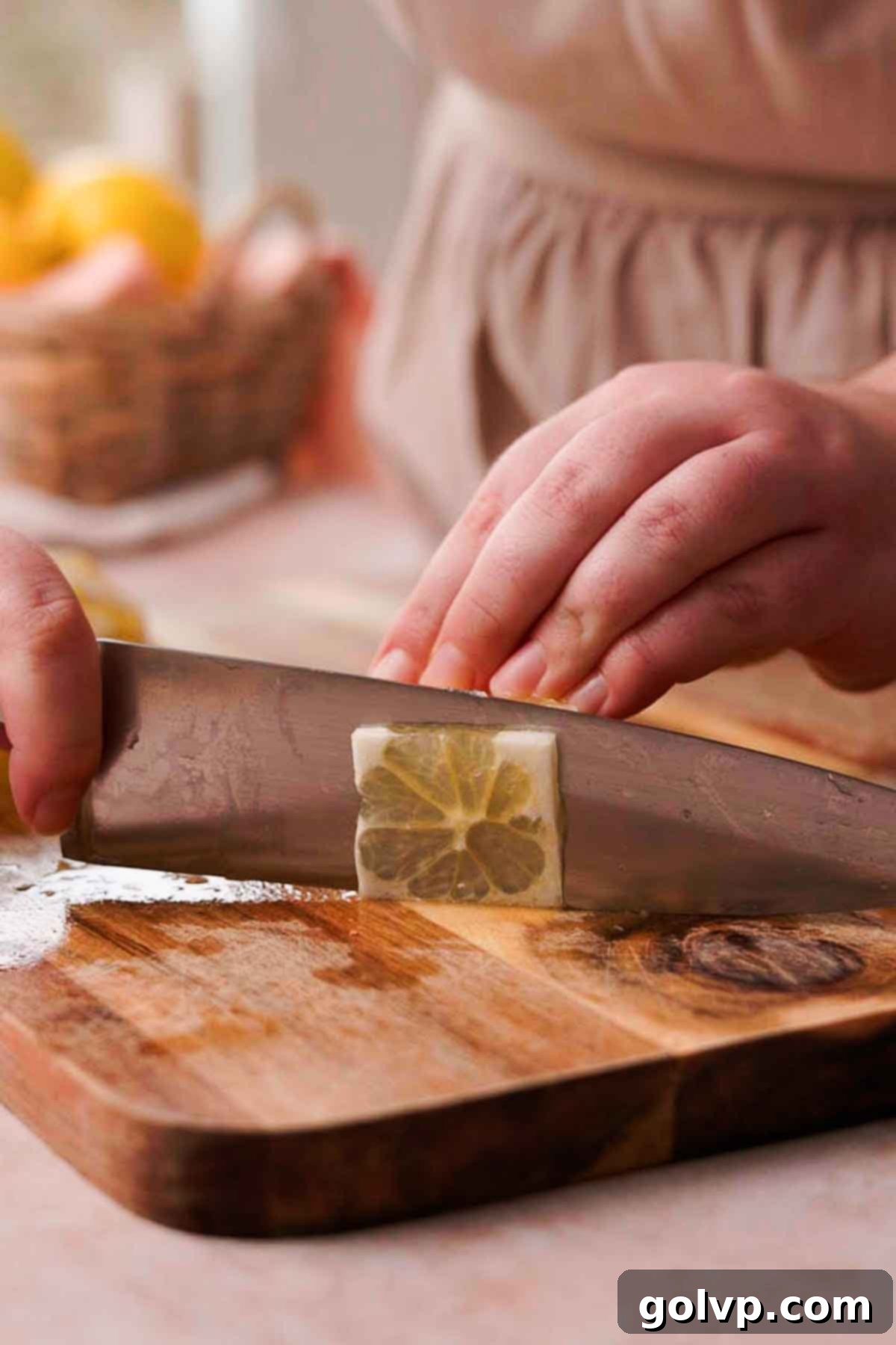 A large knife expertly slicing thin, uniform rounds of lemon from a prepared log on a cutting board, removing any visible seeds.