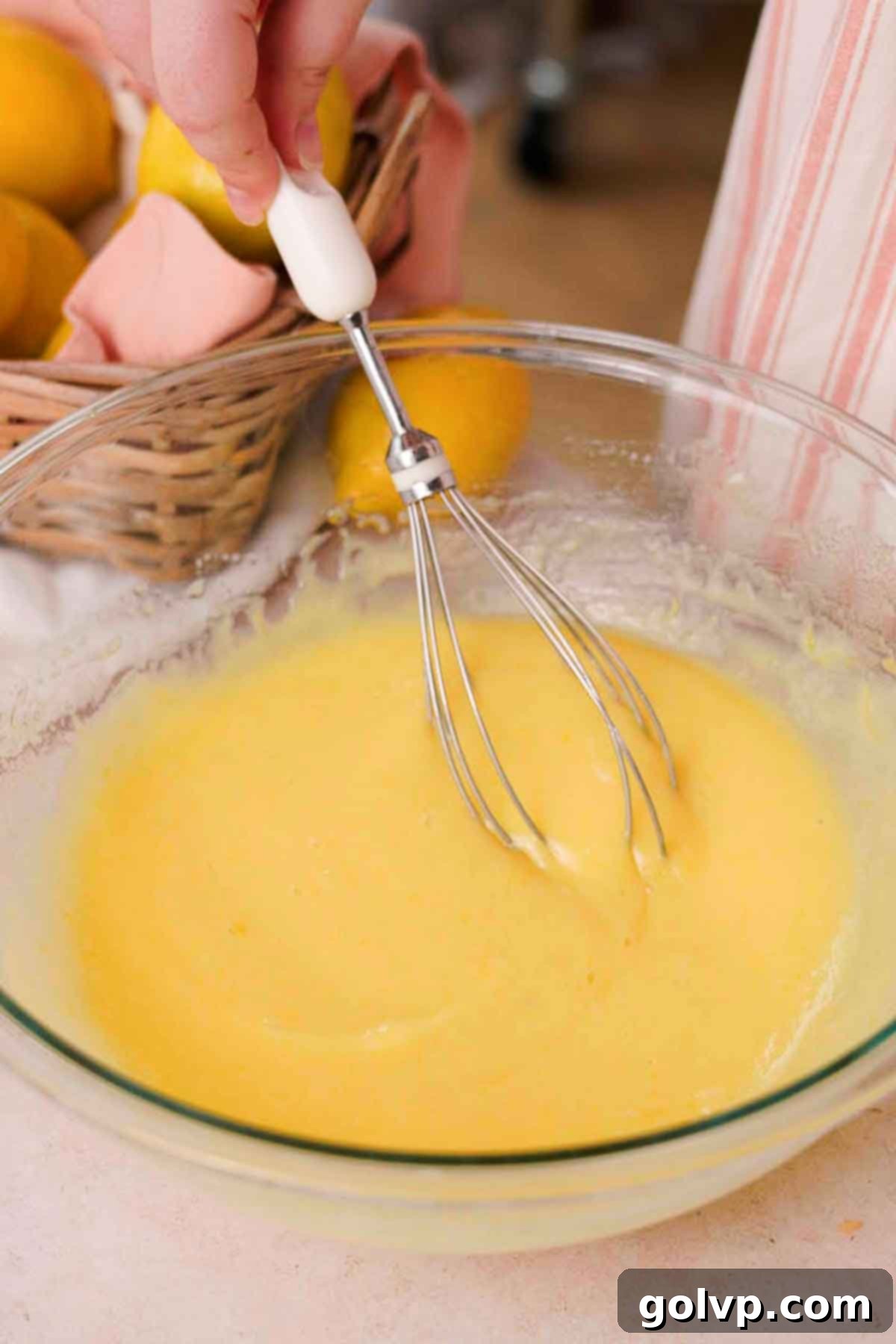 Various wet ingredients, including olive oil, lemon juice, vanilla extract, and Greek yogurt, being whisked together in a glass bowl.