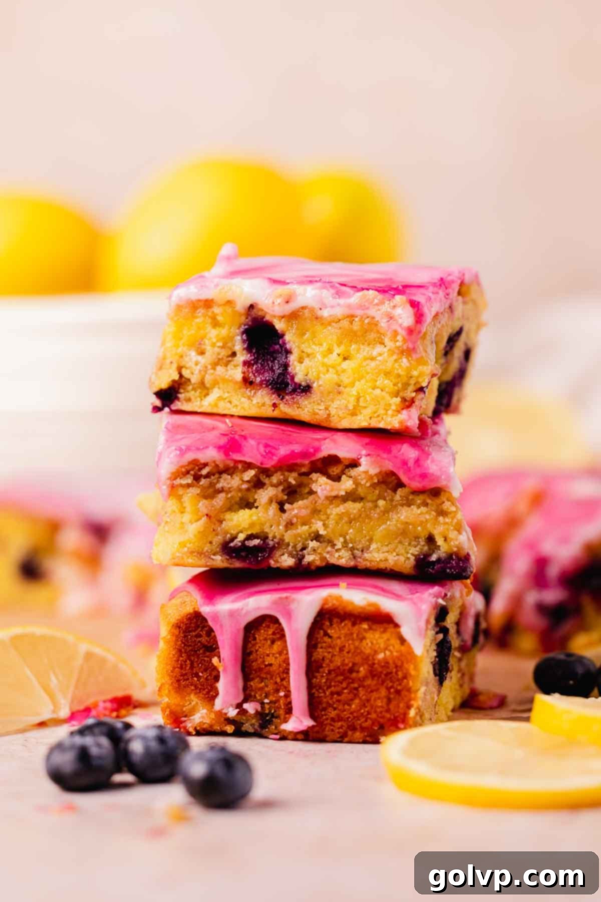 Stack of fudgy blueberry lemon brownies with a swirled white and purple glaze, showcasing their delicious texture and vibrant fruit