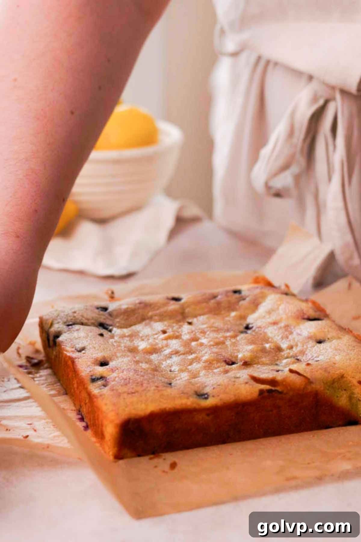 Freshly baked blueberry brownies, slightly puffed, resting in the square baking pan on parchment paper after baking