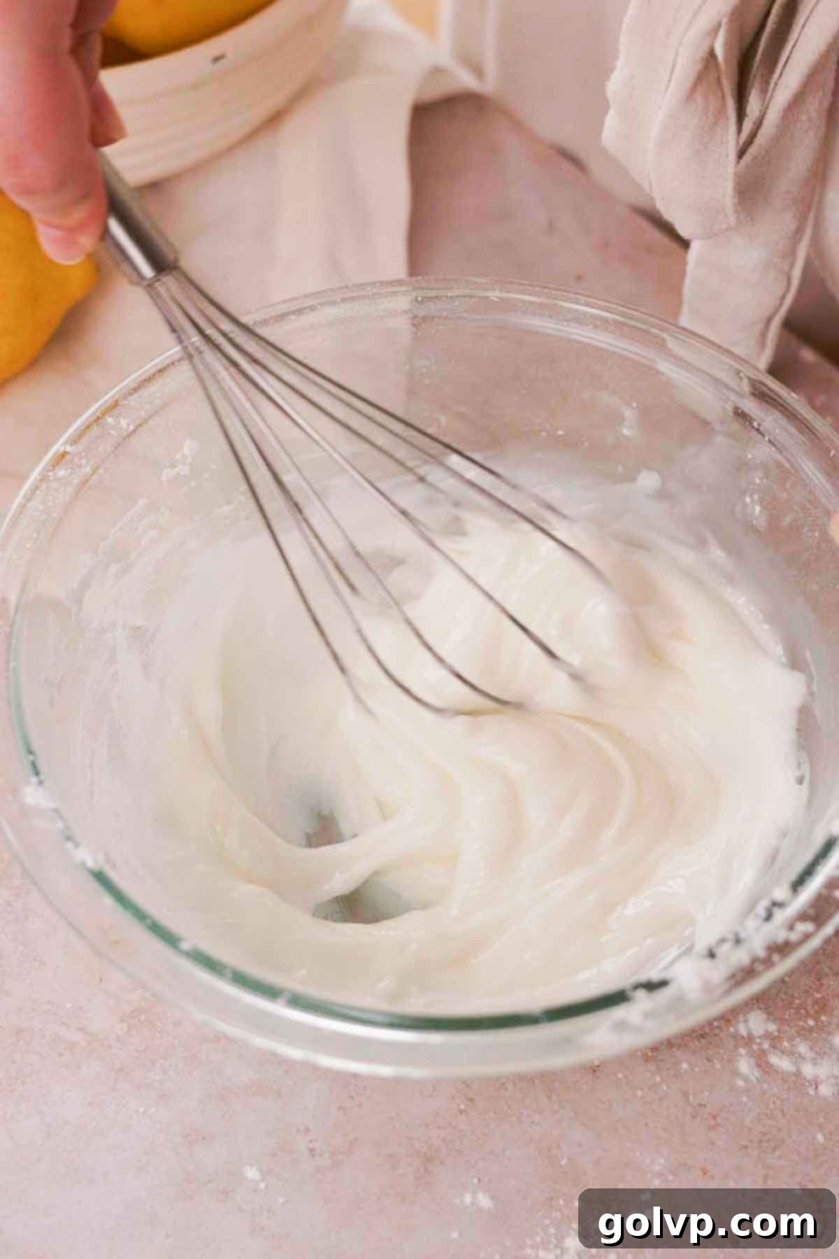 Whisking together the white lemon glaze for blueberry brownies in a bowl
