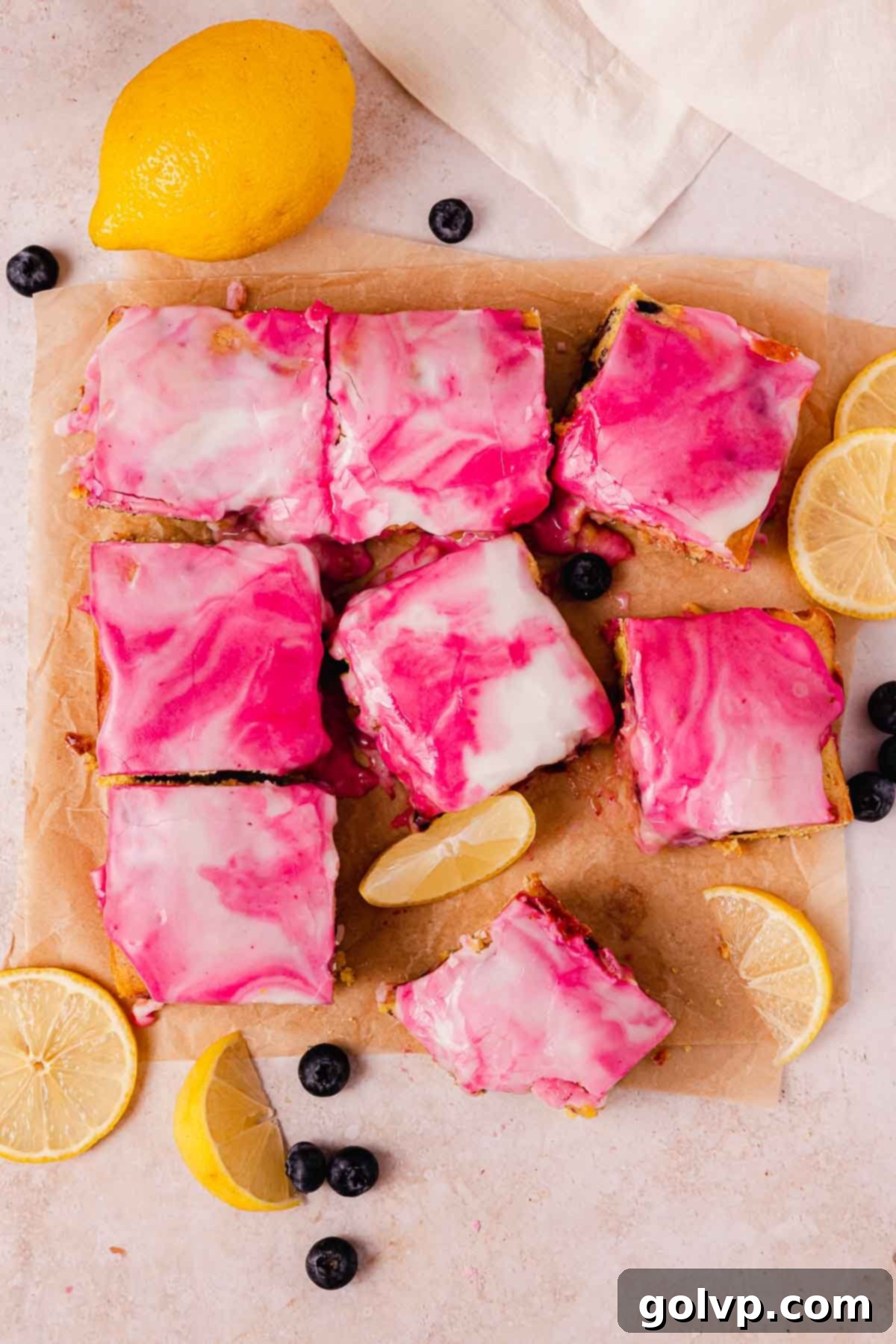 Glazed blueberry lemon brownies with swirled white and purple glaze, resting on parchment paper after setting, ready for slicing