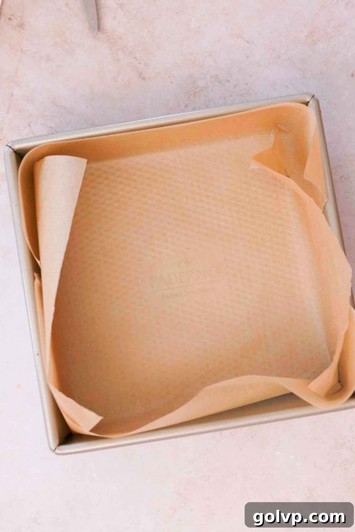 Lining a square baking pan with parchment paper, an essential first step for easy removal of brownies