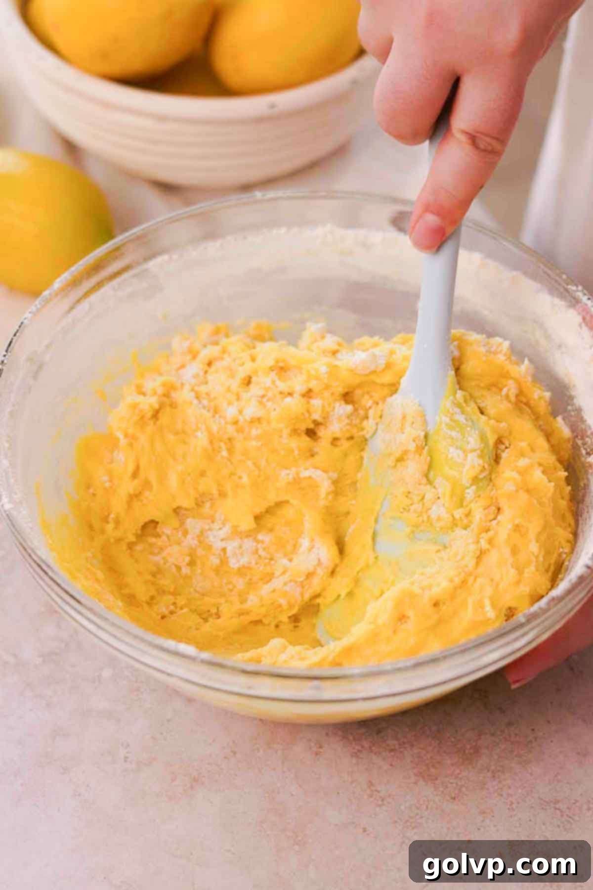 Gently folding brownie batter with a spatula in a large glass bowl, just until no dry streaks of flour remain