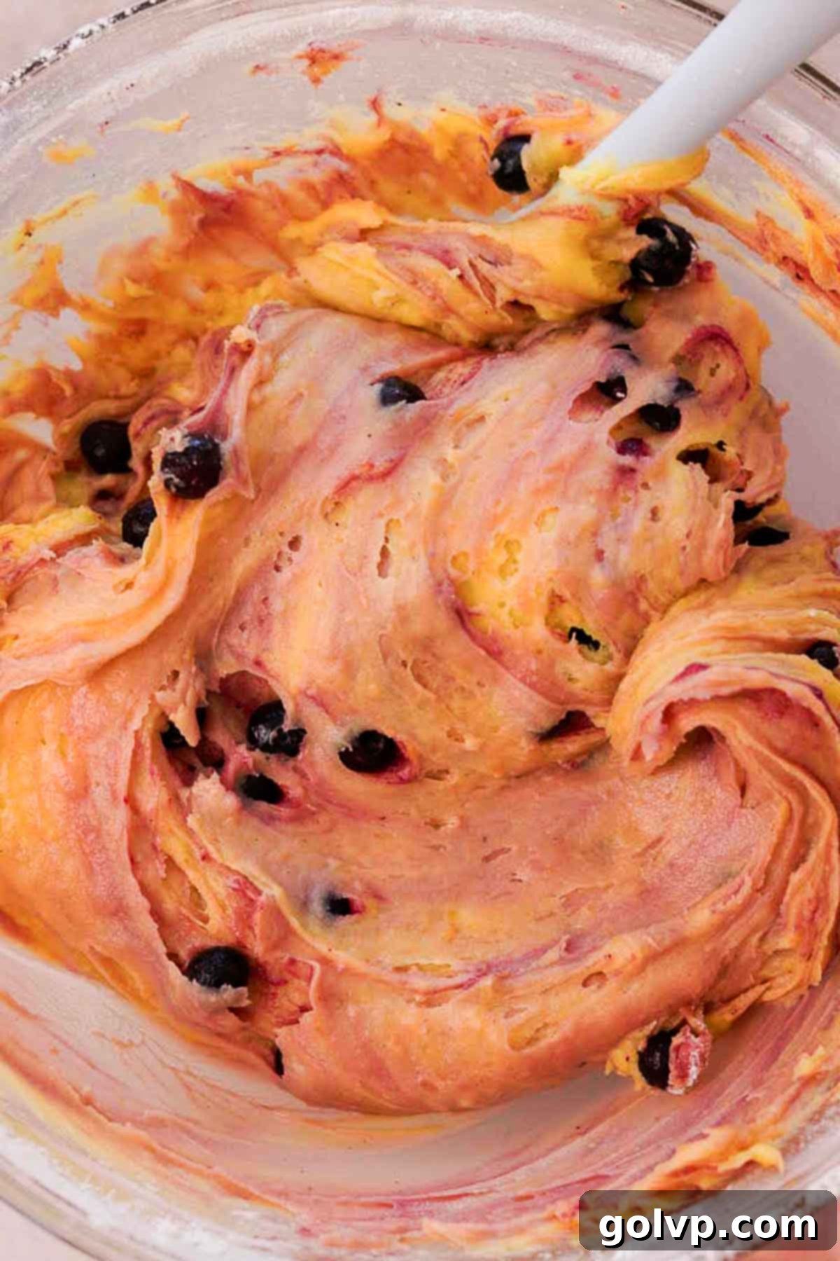 Gently folded brownie batter with flour-coated blueberries visible throughout, ready for the baking pan