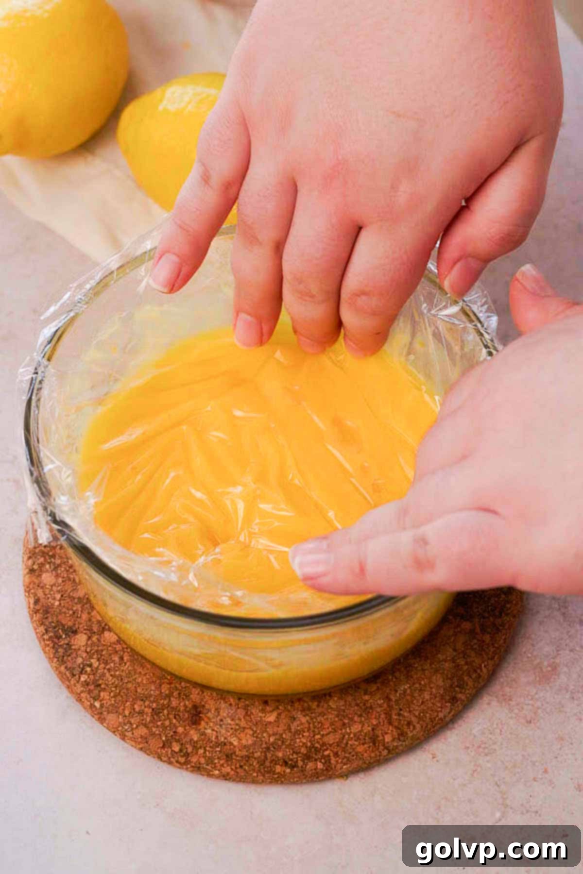 covering lemon curd in bowl with plastic wrap