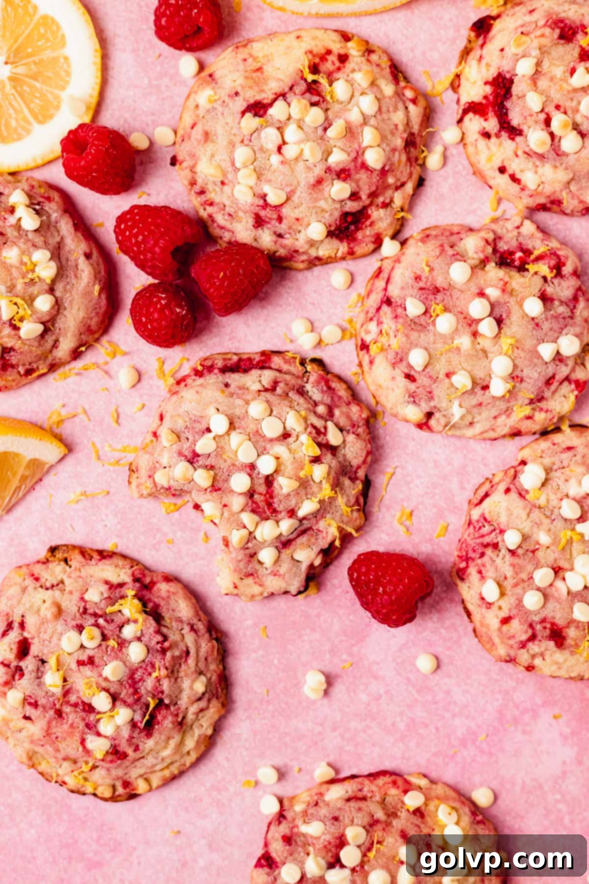 Close-up of freshly baked lemon raspberry cookies with mini white chocolate chips on top, showcasing crisp edges and soft centers and vibrant red raspberry swirls