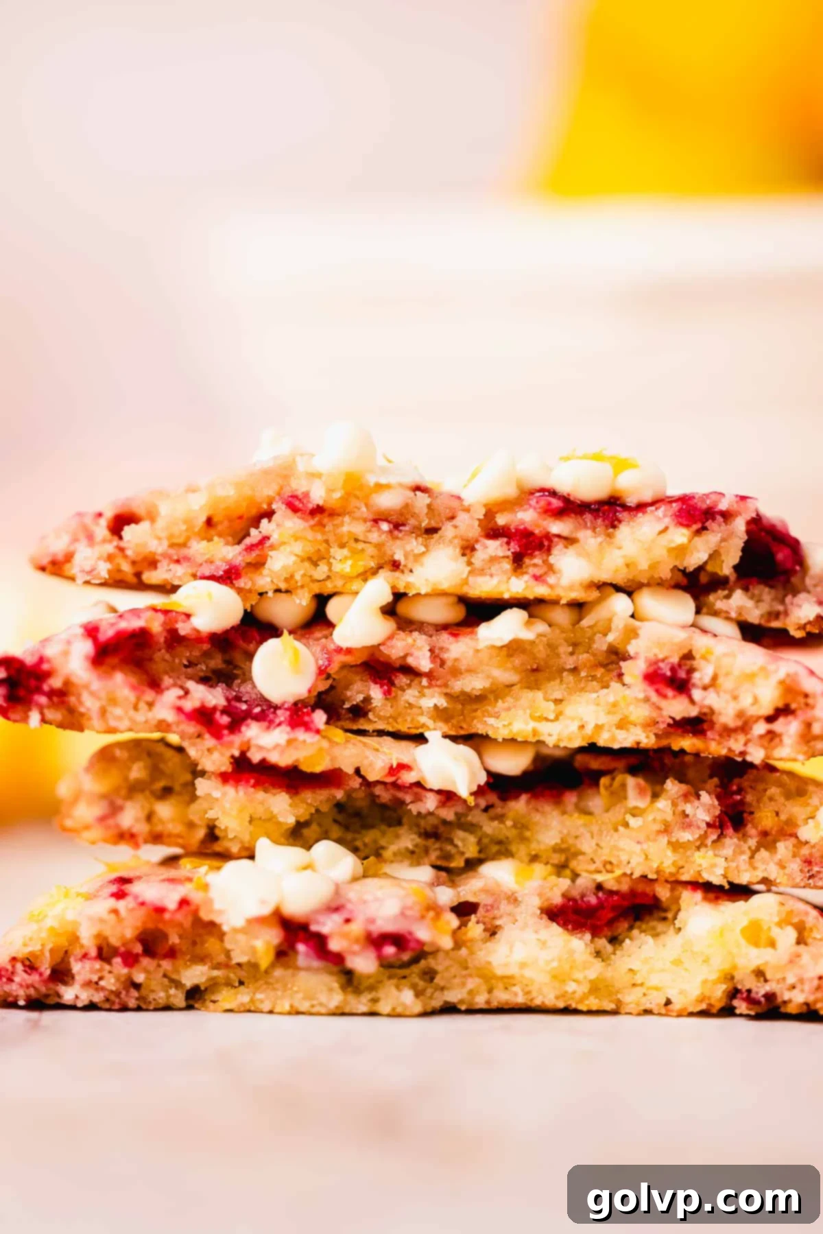 Stack of freshly baked lemon raspberry cookies with visible swirls and white chocolate chips on a cooling rack
