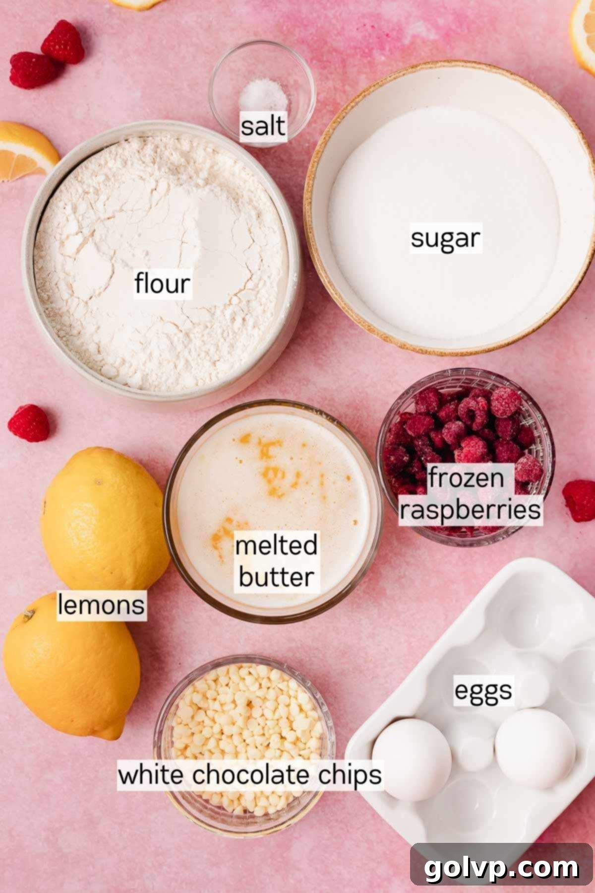Small bowls containing key ingredients for lemon raspberry cookies: fresh lemons, frozen raspberries, high-quality white chocolate chips, all-purpose flour, melted butter, and granulated sugar