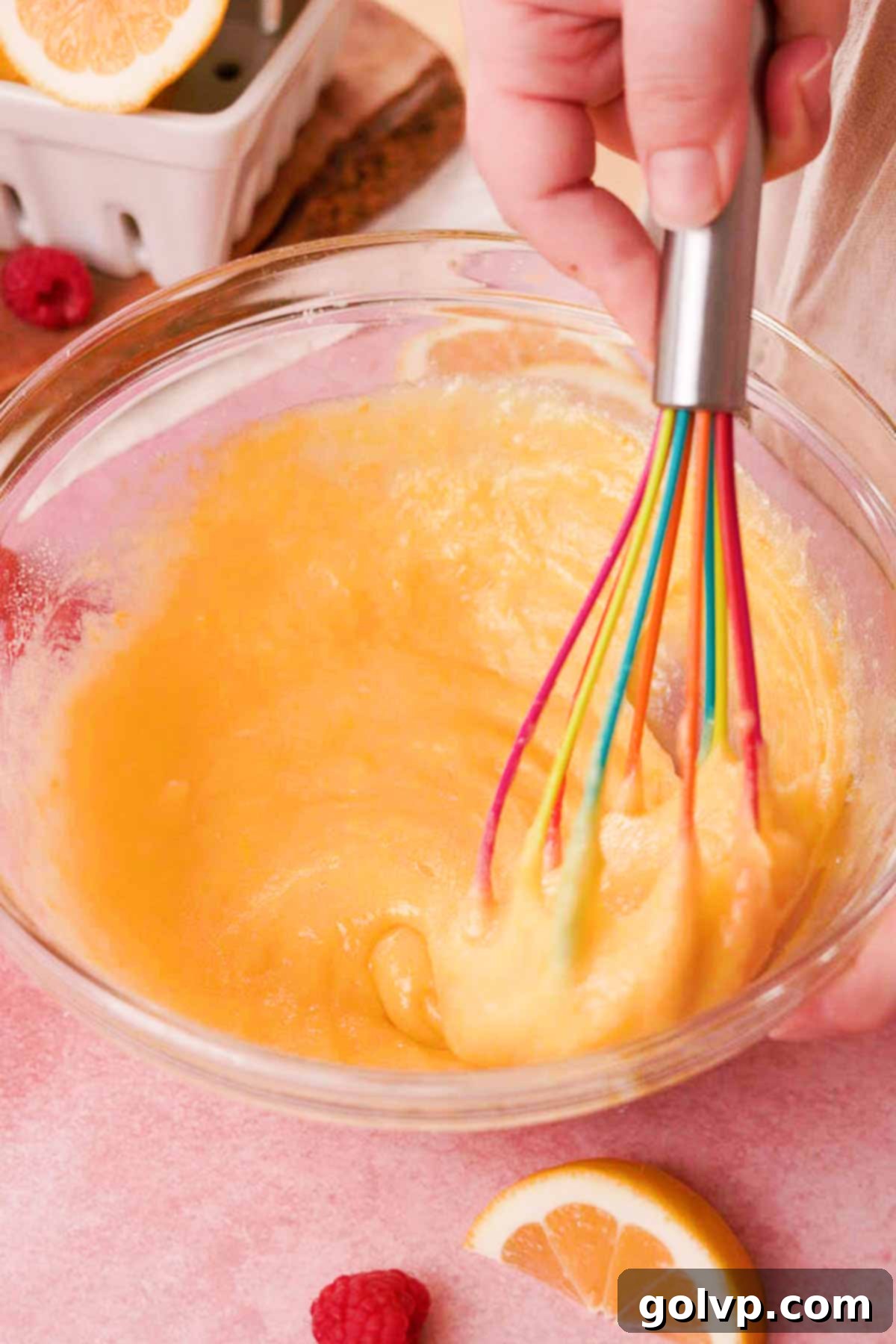 Gently whisking eggs into the lemon sugar mixture in a large glass bowl with a silicone whisk to avoid excess air bubbles.