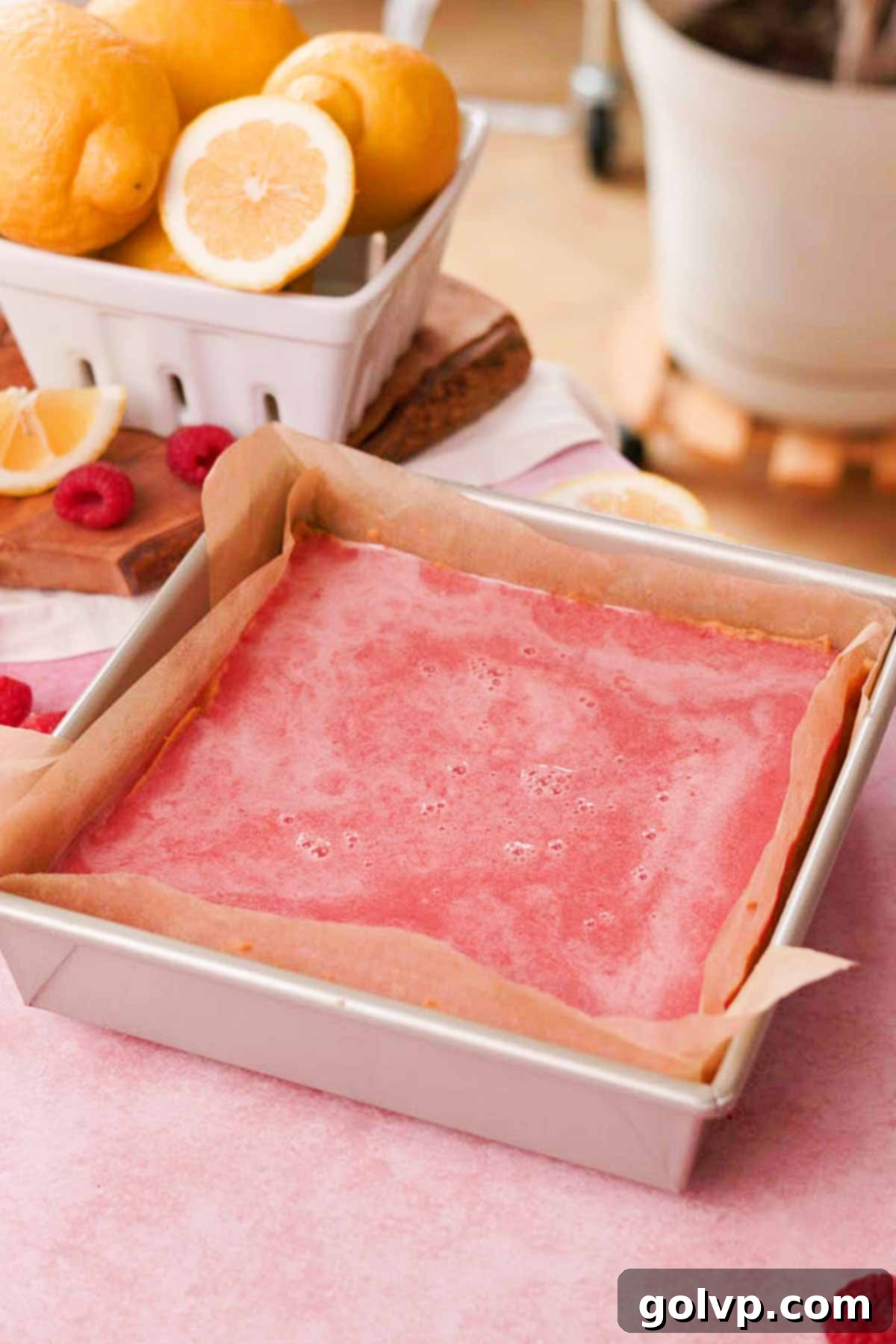 Ready-to-bake lemon raspberry bars in a square baking pan with the filling poured over the pre-baked shortbread crust.