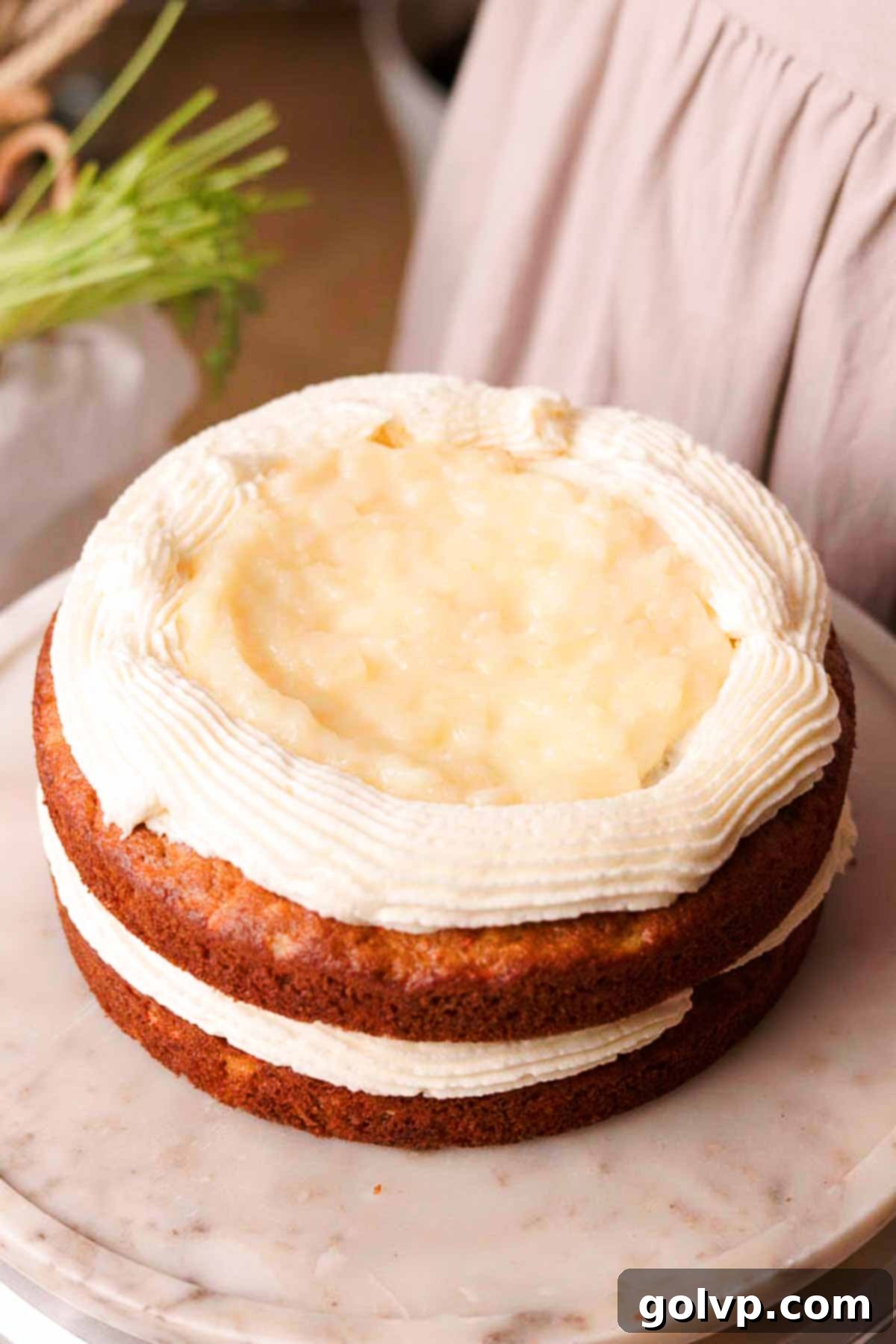 stacking and filling cake layers with cream cheese frosting and pineapple filling