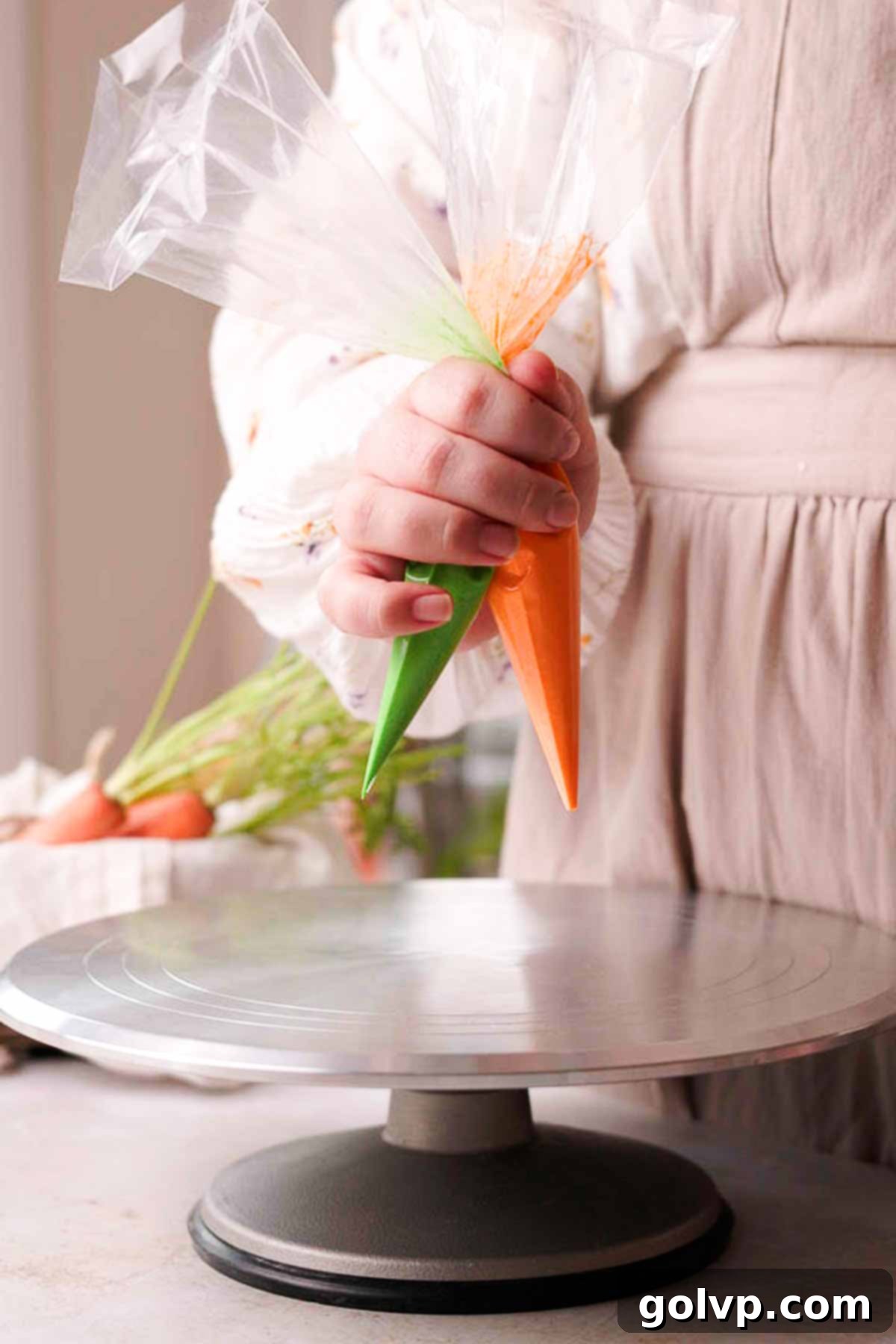 holding two piping bags, one green and one orange frosting