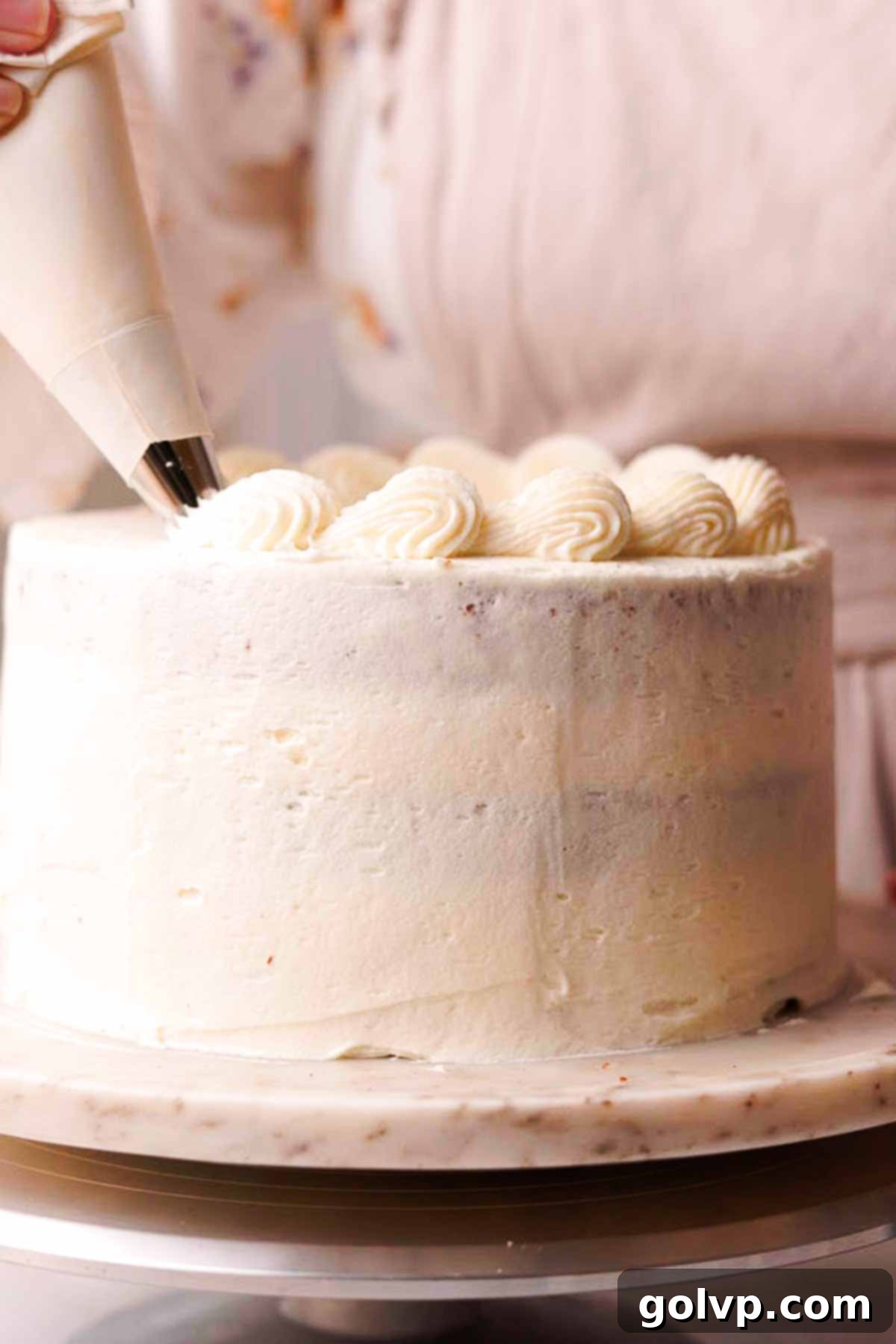 piping frosting border with open star tip on top of carrot cake