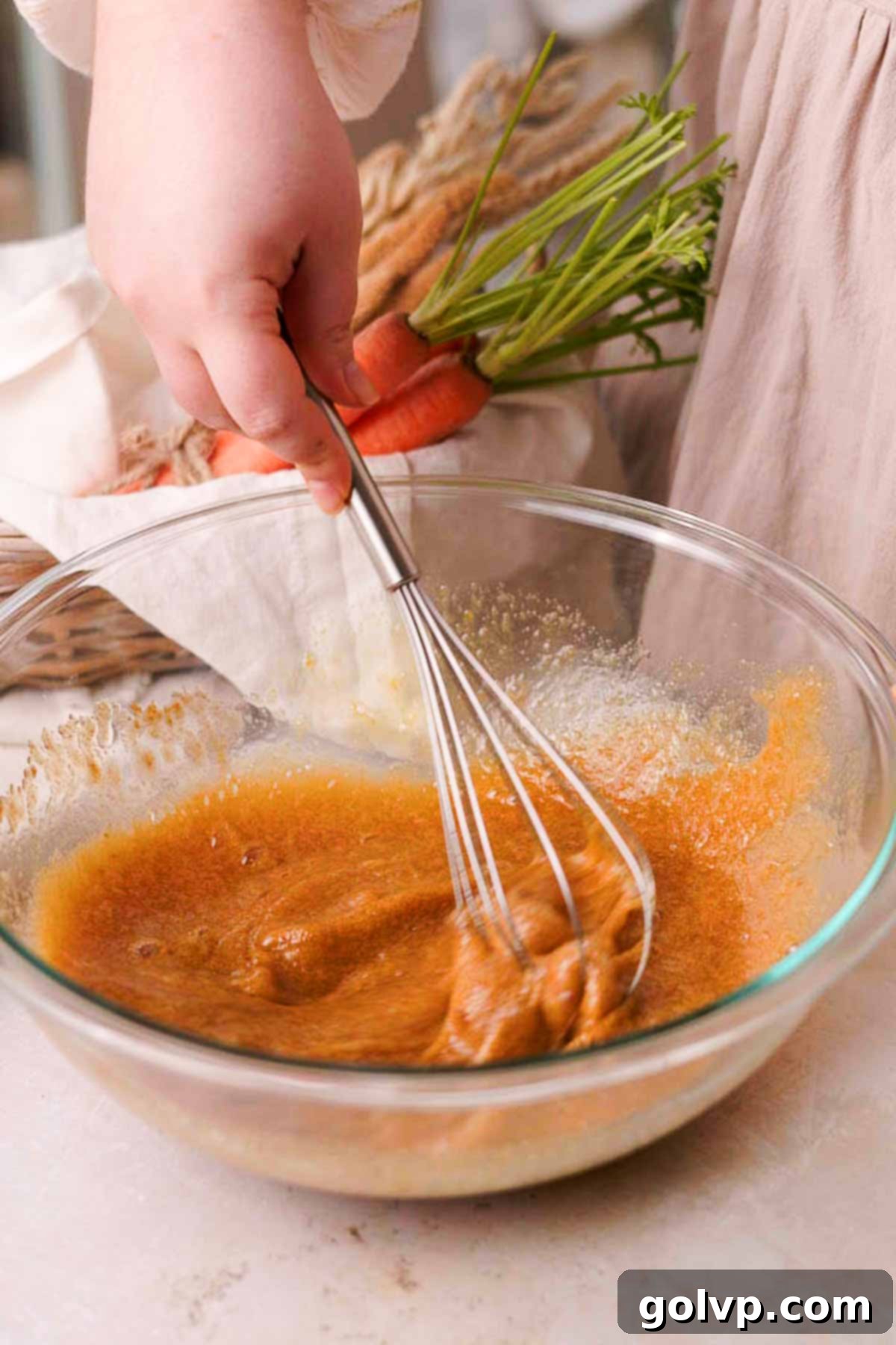 whisking eggs and sugar together in a large glass bowl with a hand whisk