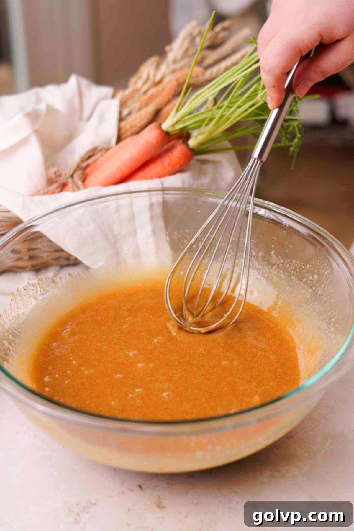 carrot cake wet ingredients for batter in a large glass bowl with a whisk