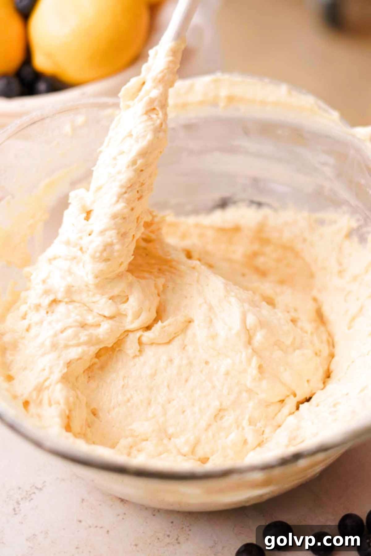 Gently folding cake batter with dry ingredients (flour, baking soda, baking powder) into the wet mixture in a large glass bowl.